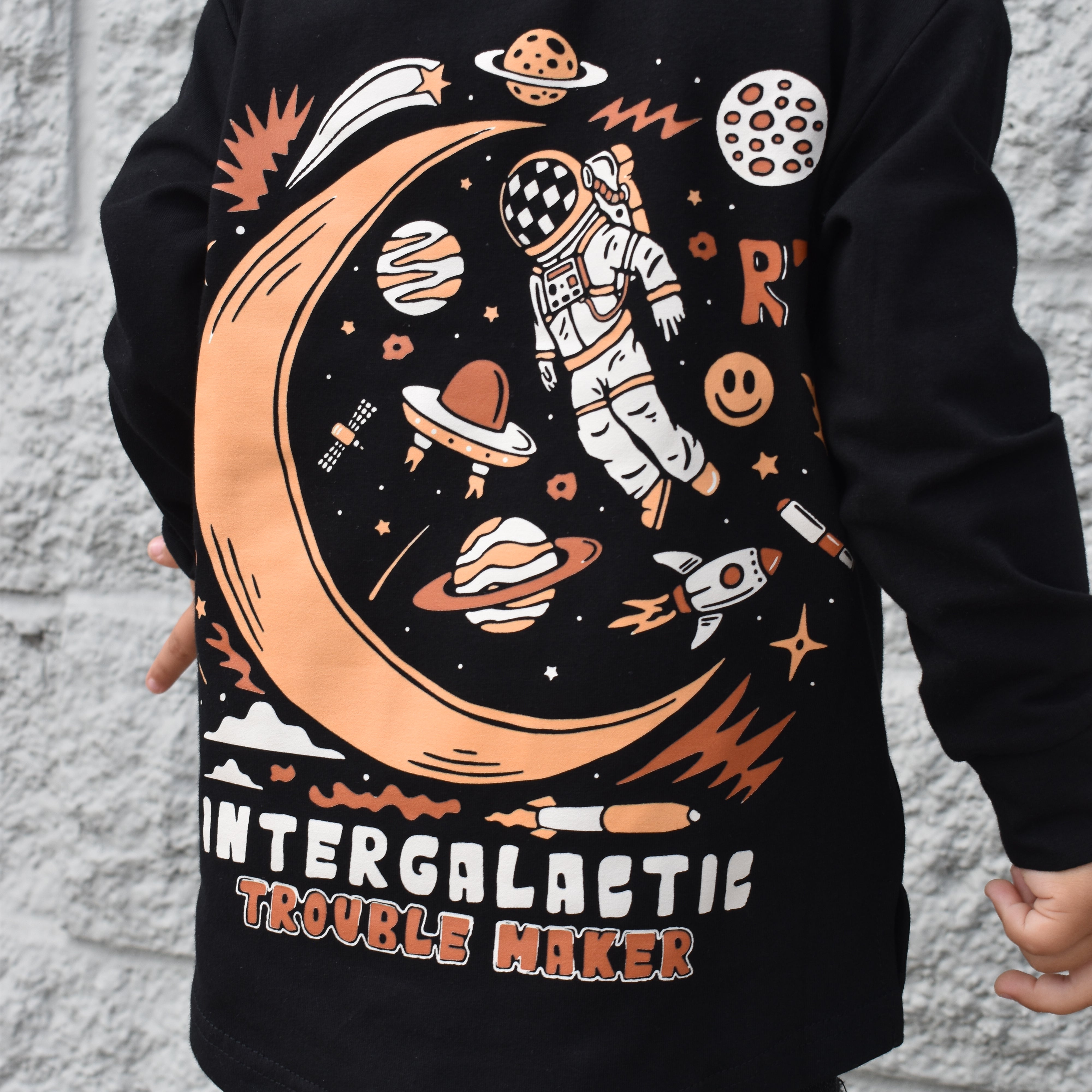 Lifestyle photo of boy wearing black Intergalactic Troublemaker long sleeve