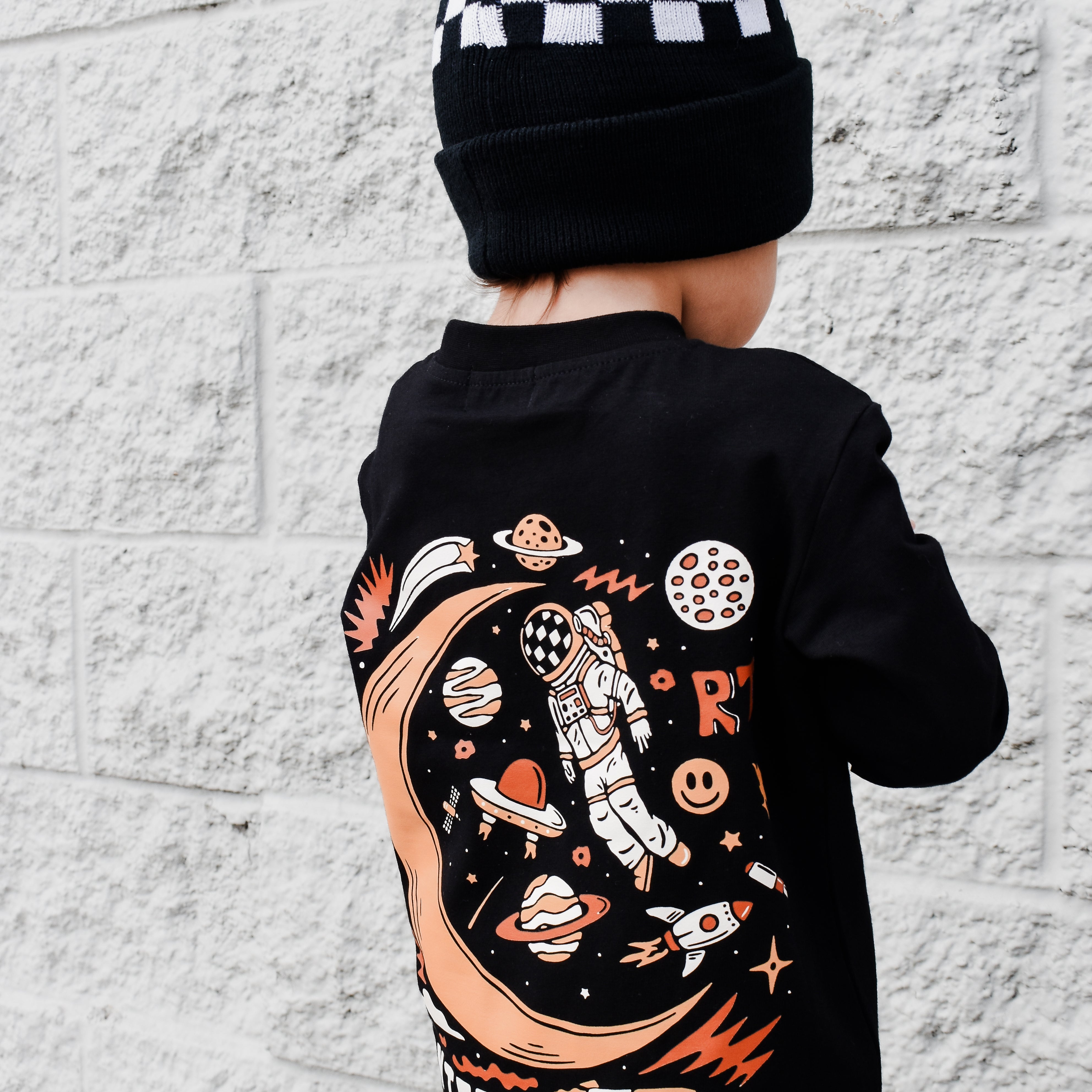 Lifestyle photo of boy wearing black Intergalactic Troublemaker long sleeve