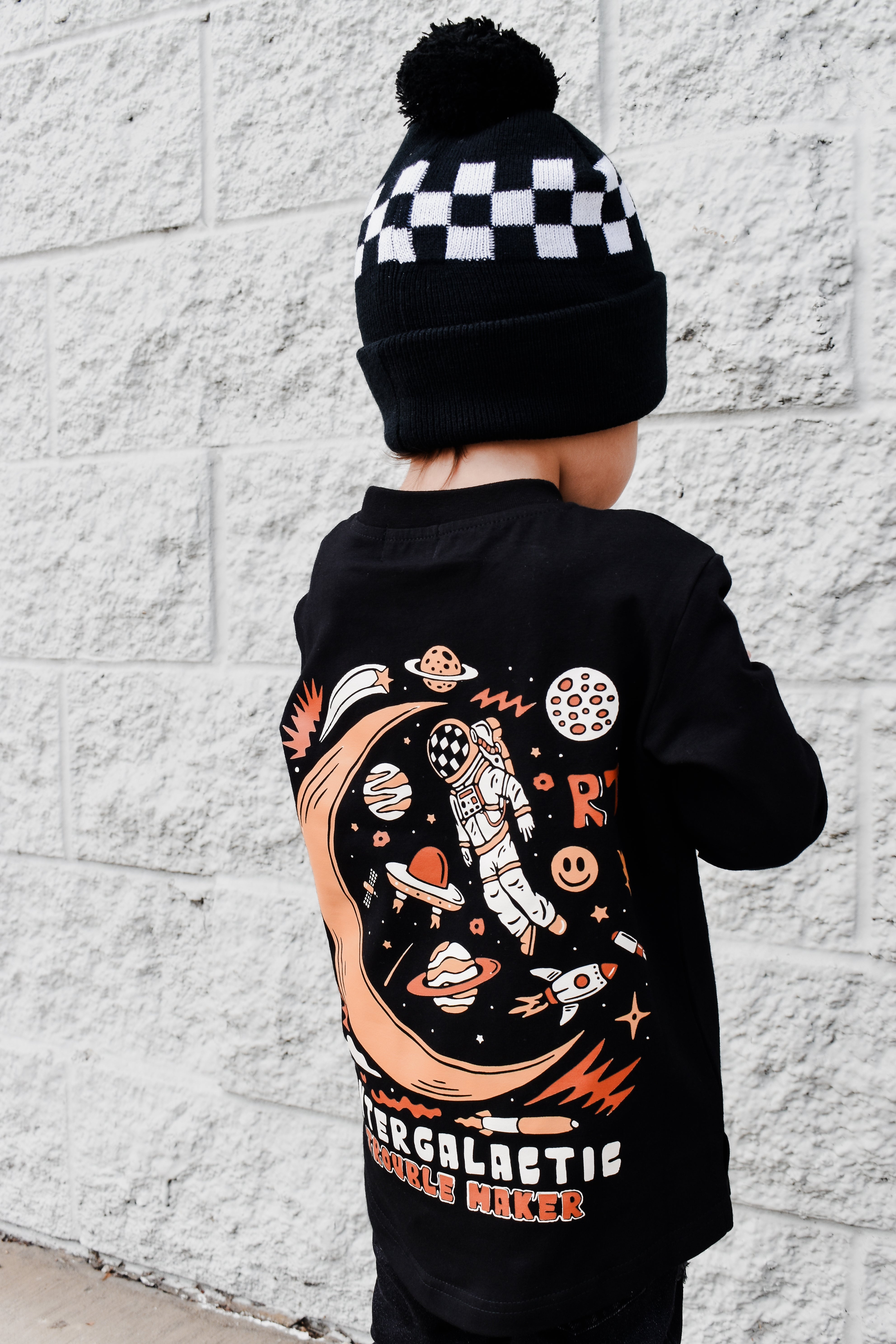 Lifestyle photo of boy wearing black Intergalactic Troublemaker long sleeve