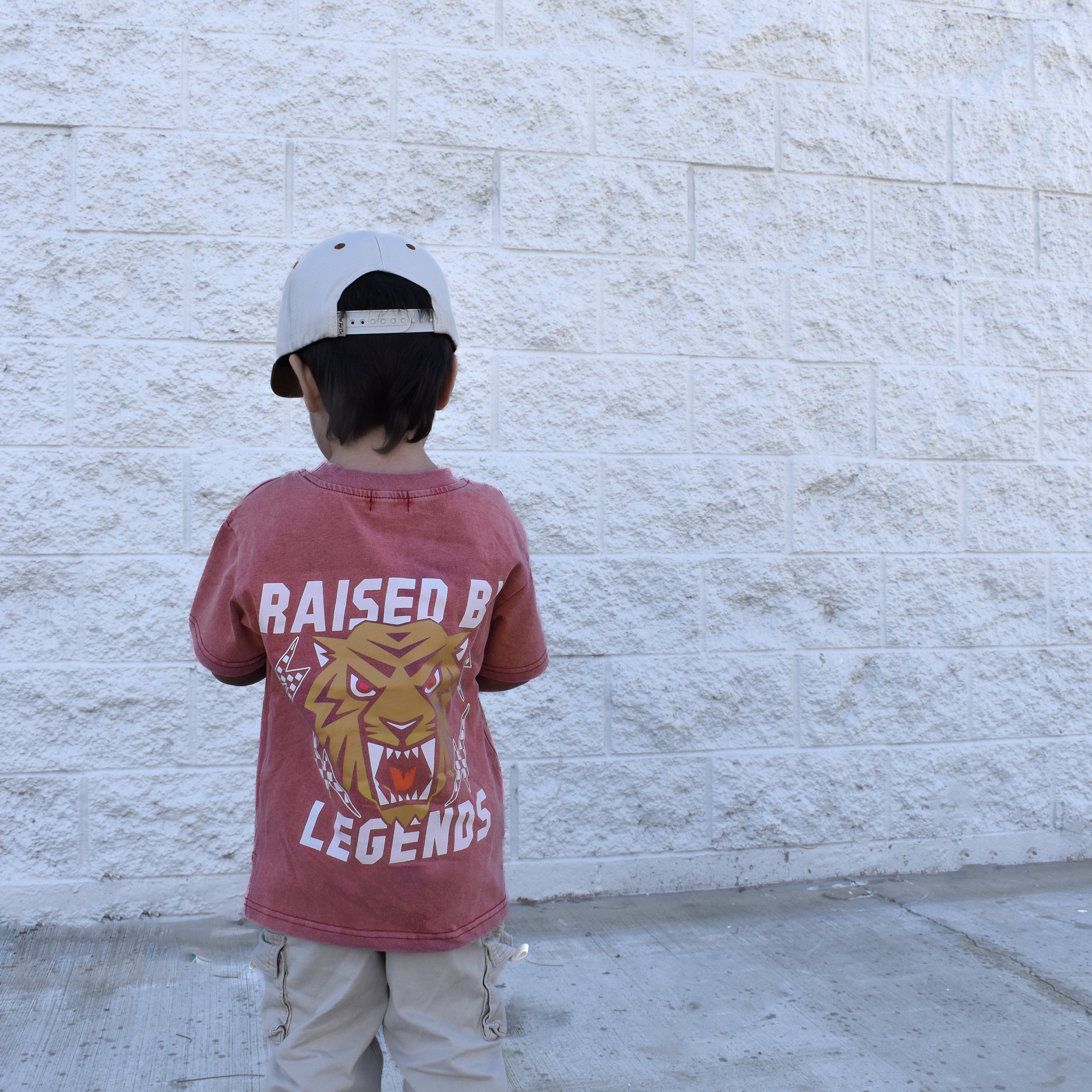 Cool kid wearing red acid wash Raised by Legends tiger t-shirt