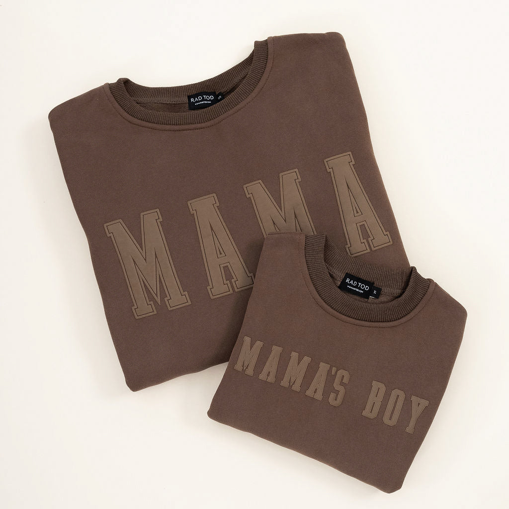 Brown “Mama’s Boy” crewneck with slightly lighter brown lettering, laid flat on a neutral background. Matching Mama crewneck