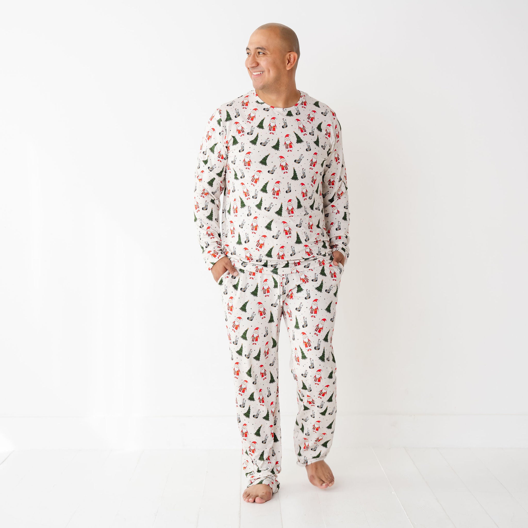 Man wearing Merry Everything Bamboo Christmas Pajamas with Santa, trees, and checkered stockings