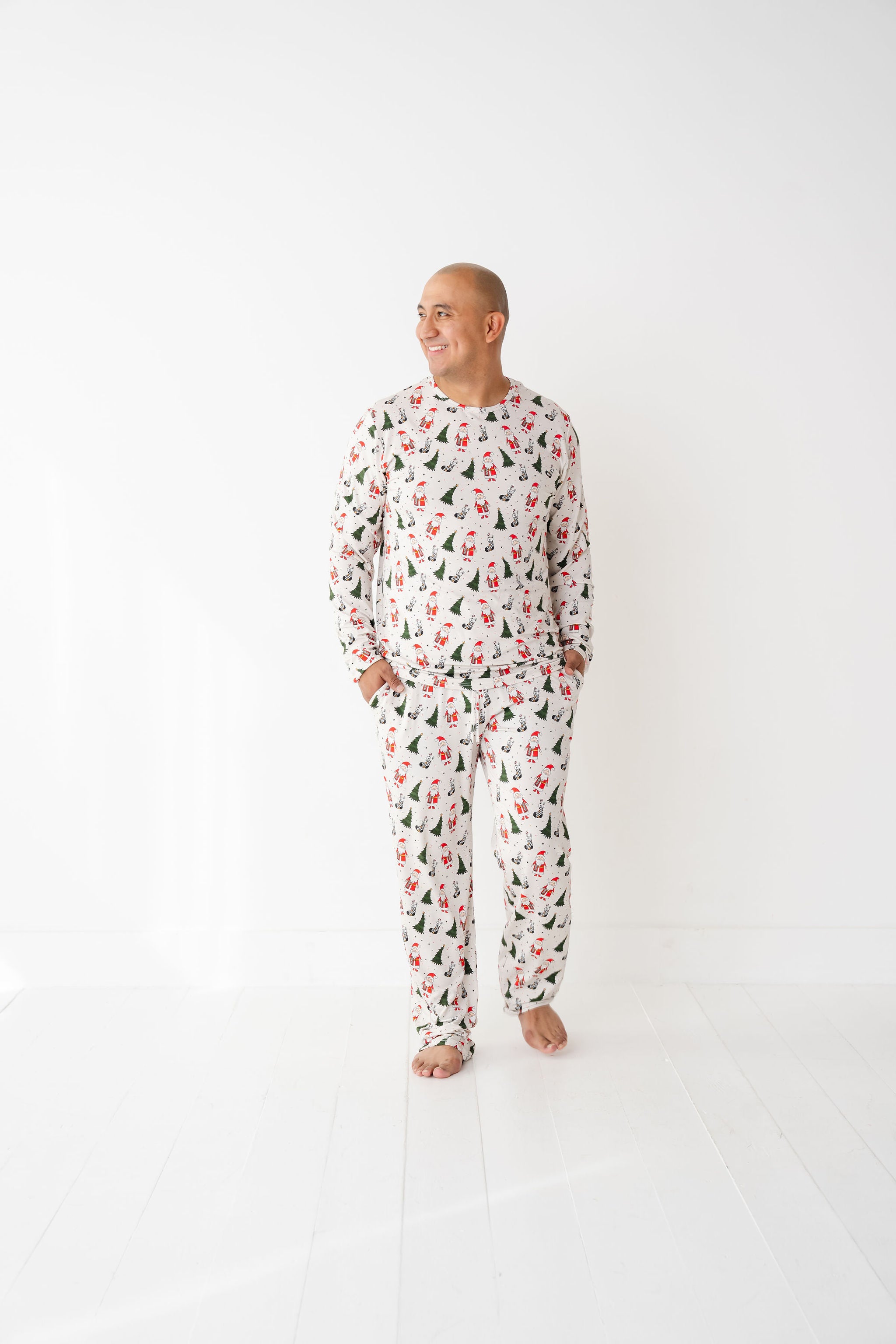 Man wearing Merry Everything Bamboo Christmas Pajamas with Santa, trees, and checkered stockings