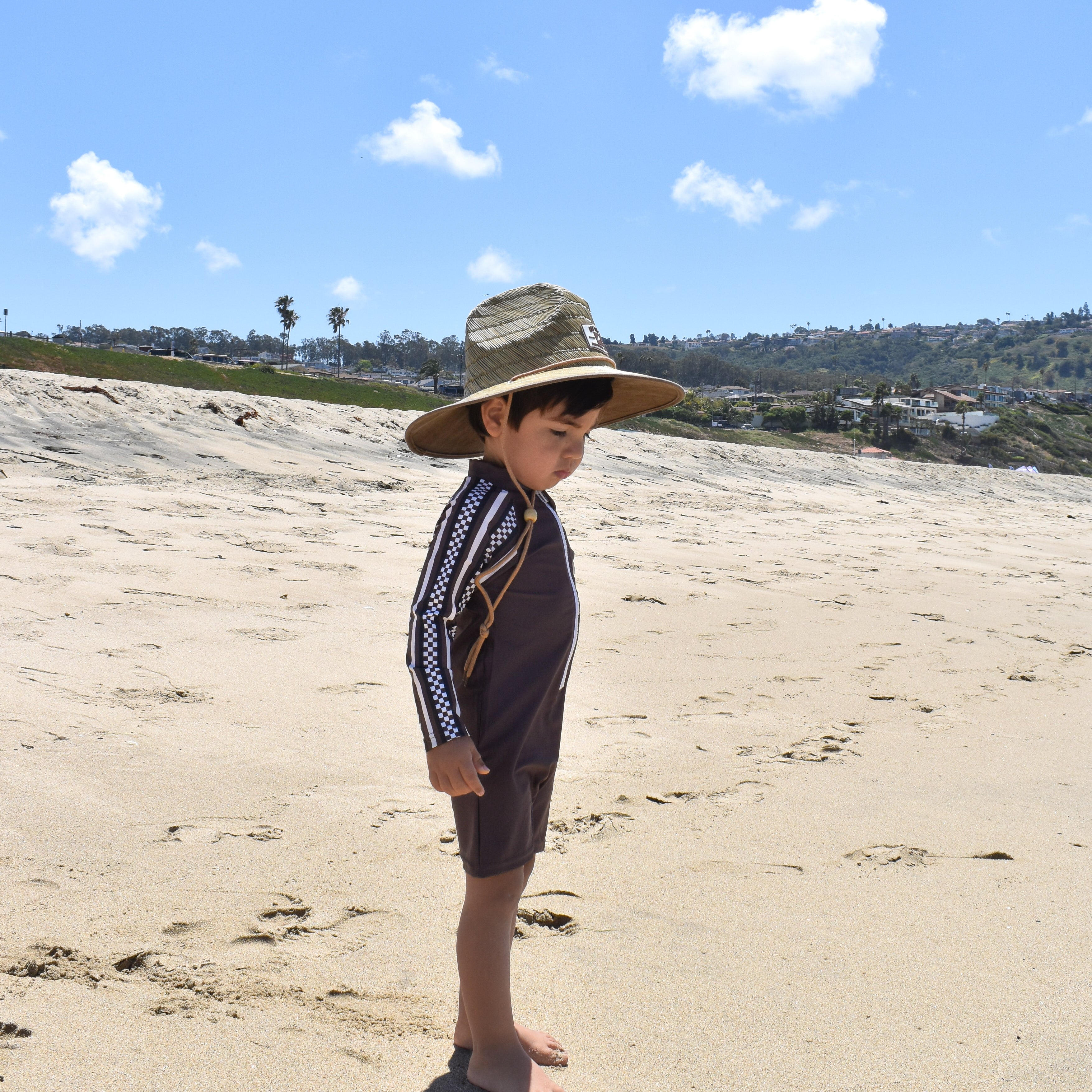 Child wearing mocha rashguard onesie at beach by rad toddler