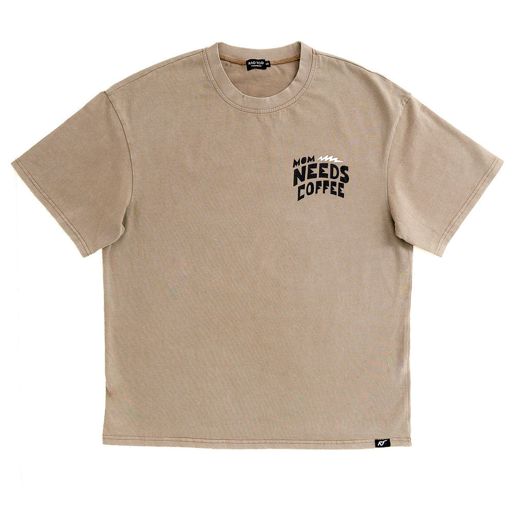 A beige short-sleeve crewneck t-shirt with a black graphic text print on the left chest reading 'MORNING NEEDS COFFEE' with a coffee cup icon, displayed flat against a white background.