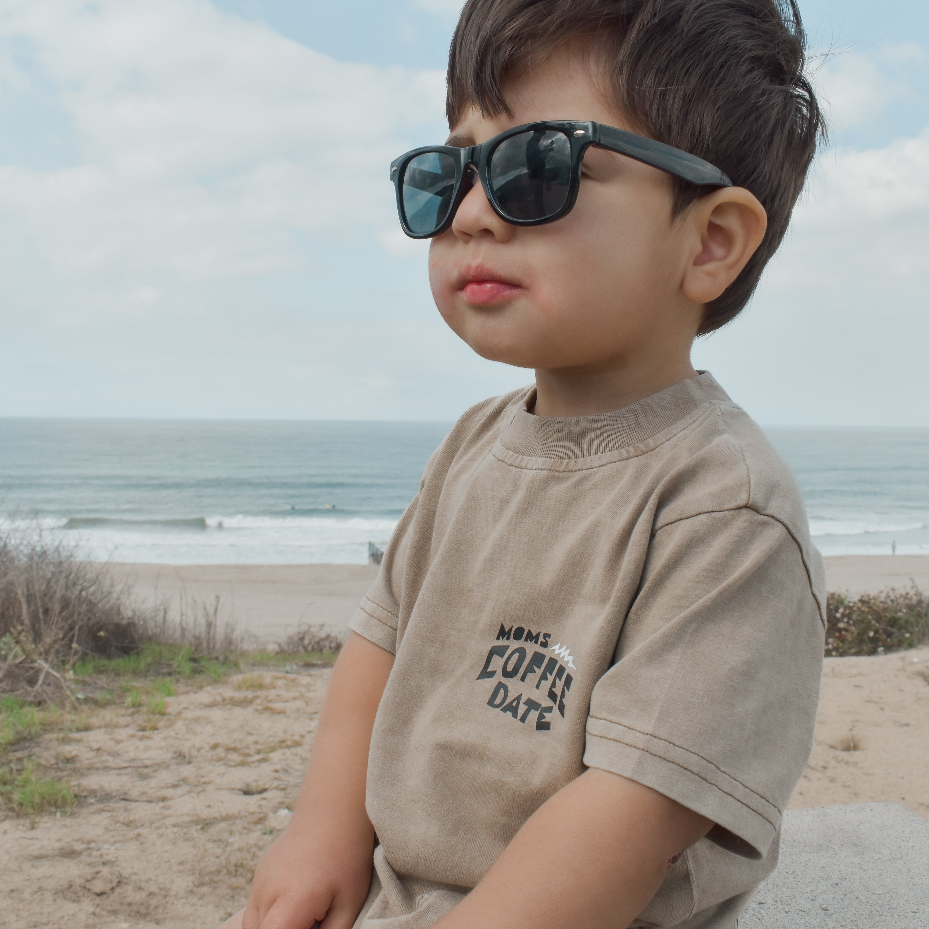 boy wearing moms coffee date t shirt stares onward probably looking at mom