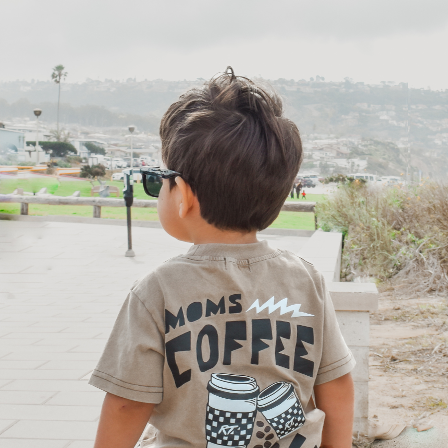 boy wearing awesome moms coffee date t shirt while staring out to the horizon