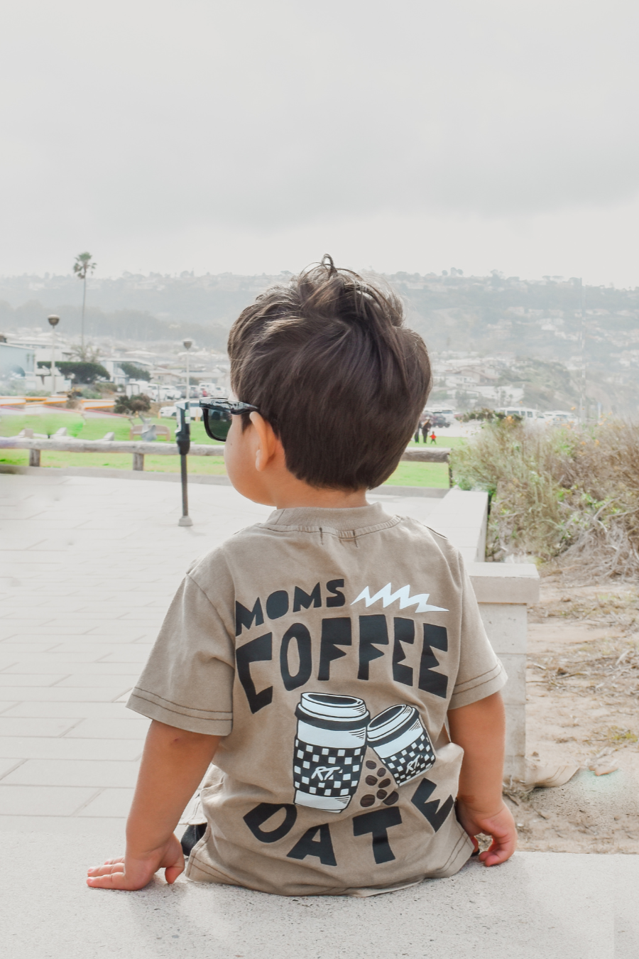 boy wearing awesome moms coffee date t shirt while staring out to the horizon