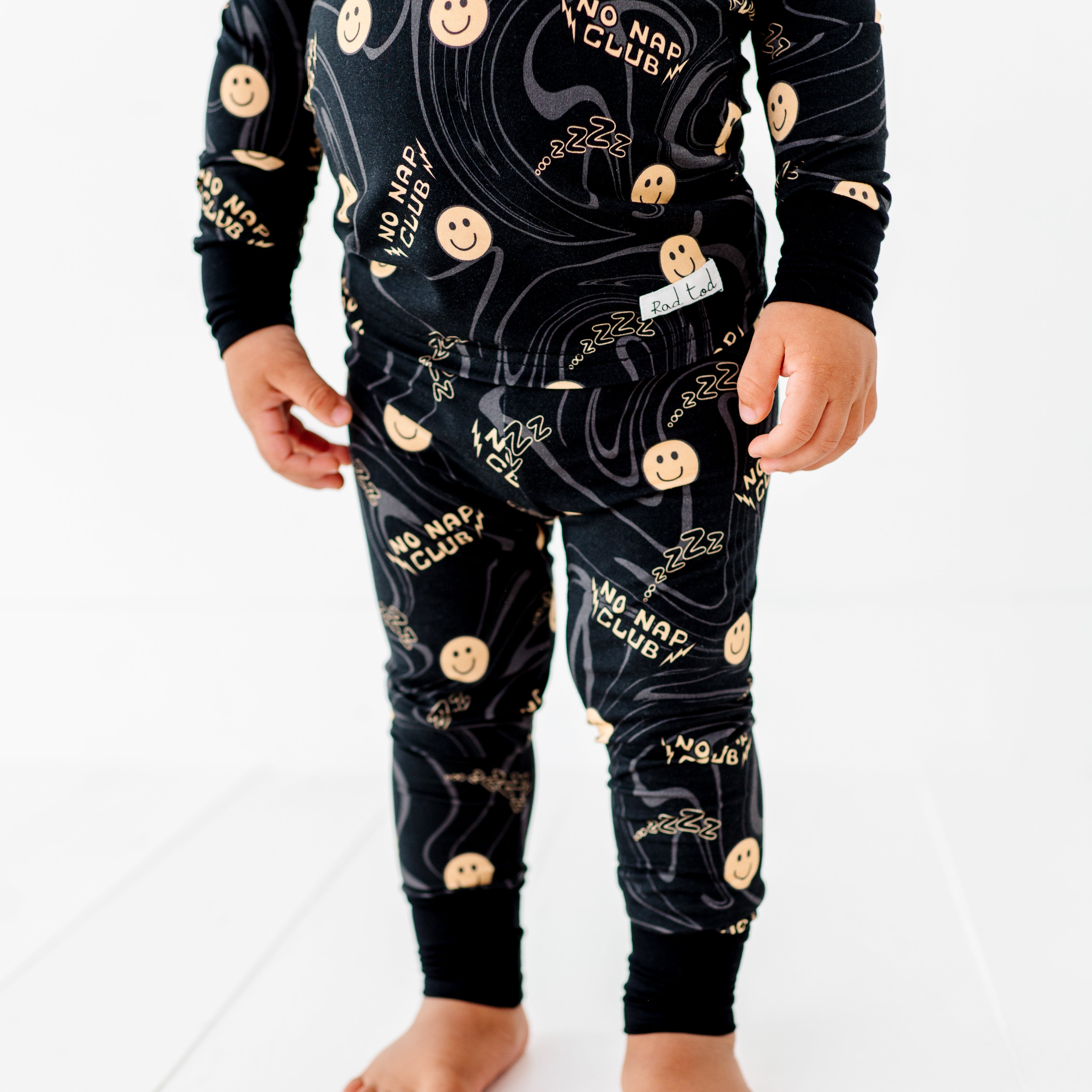 boy wearing No Nap Club bamboo 2-piece set for toddlers with smiley faces and wavy line pattern