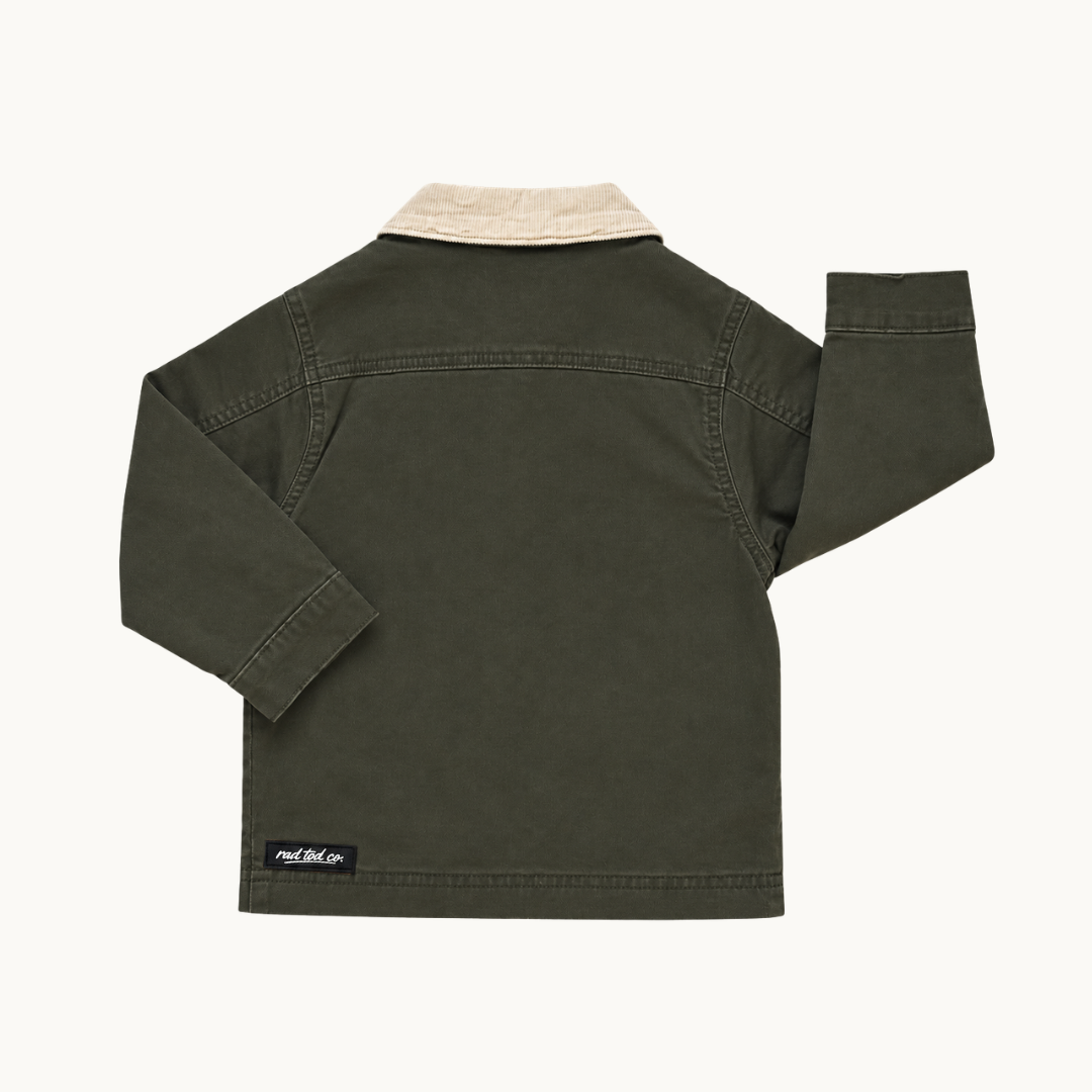 An olive green long-sleeve jacket shown from the back, featuring a light beige corduroy collar and a black brand patch near the bottom left hem, set against a plain off-white background.