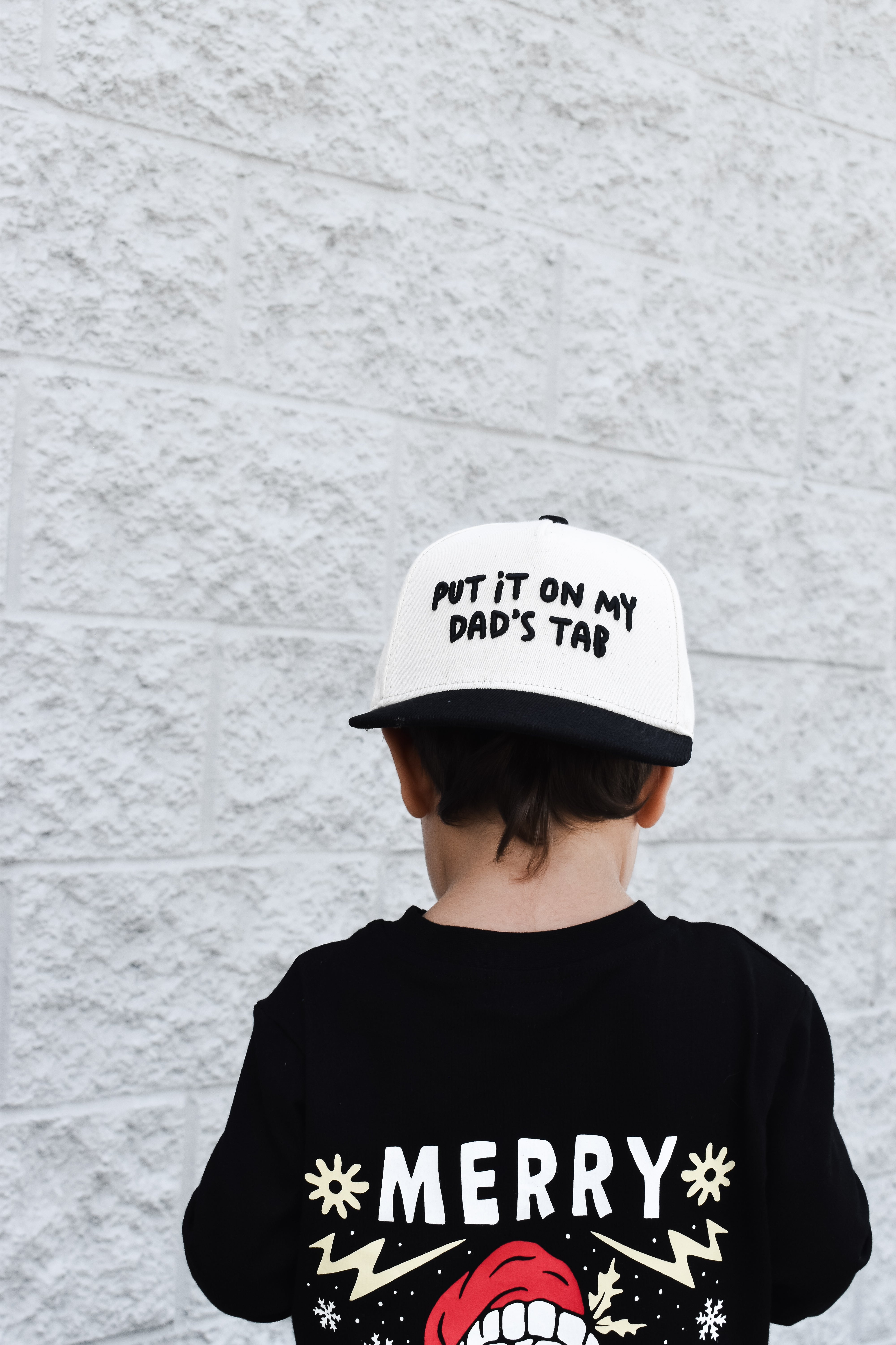 hild wearing Put It On My Dad’s Tab snapback outdoors while playing