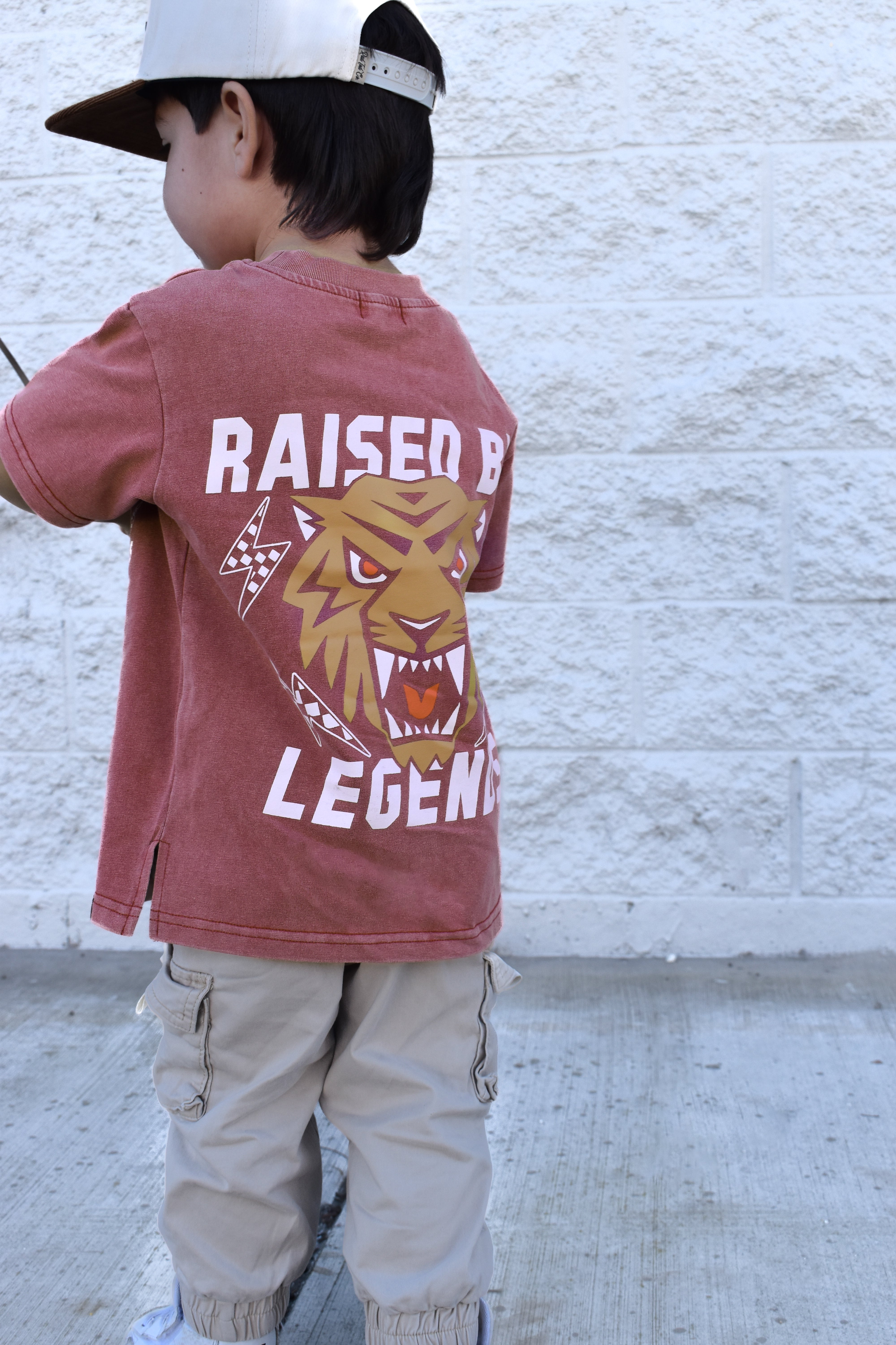 Kid wearing Raised by Legends tiger tee, red acid wash premium kids shirt