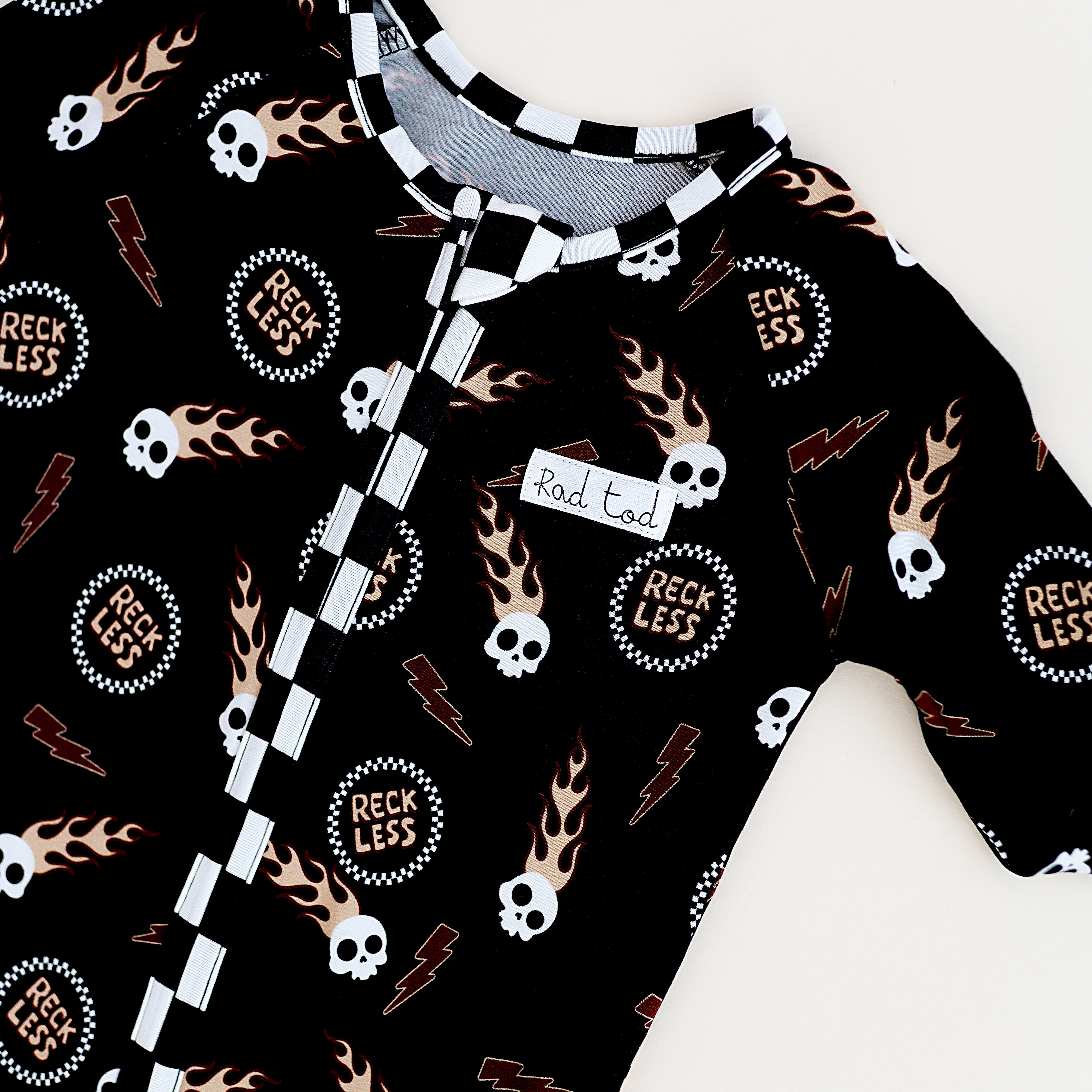Edgy toddler onesie with checker print, flaming skull, and soft bamboo fabric