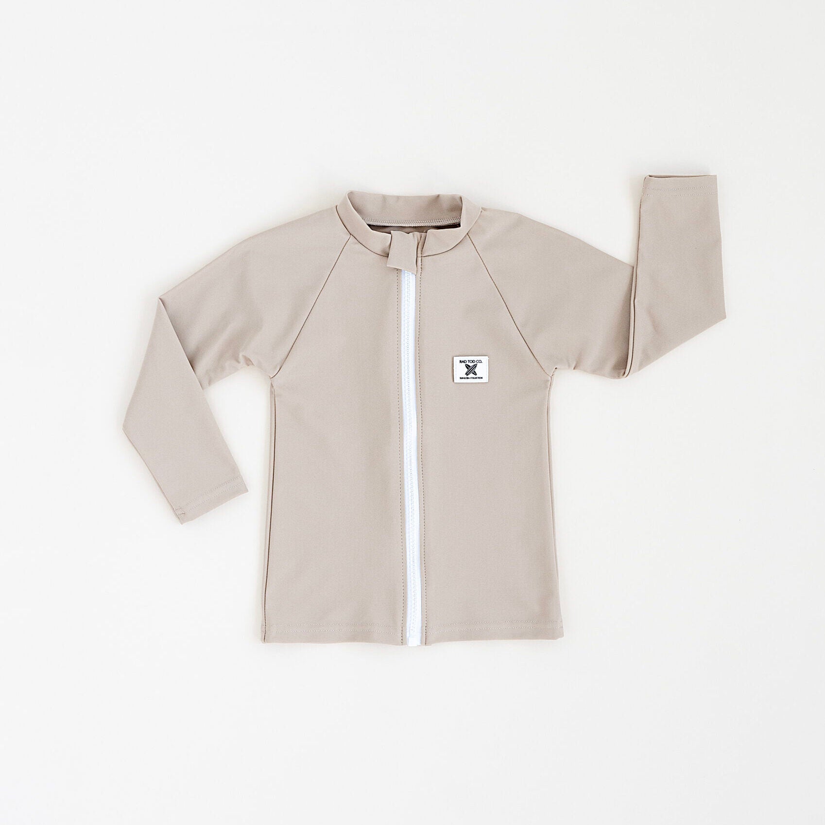 Rad Toddlers 'Sand' Rashguard Shirt with front zipper and UPF 50+ protection, perfect for pairing with board shorts for water activities.