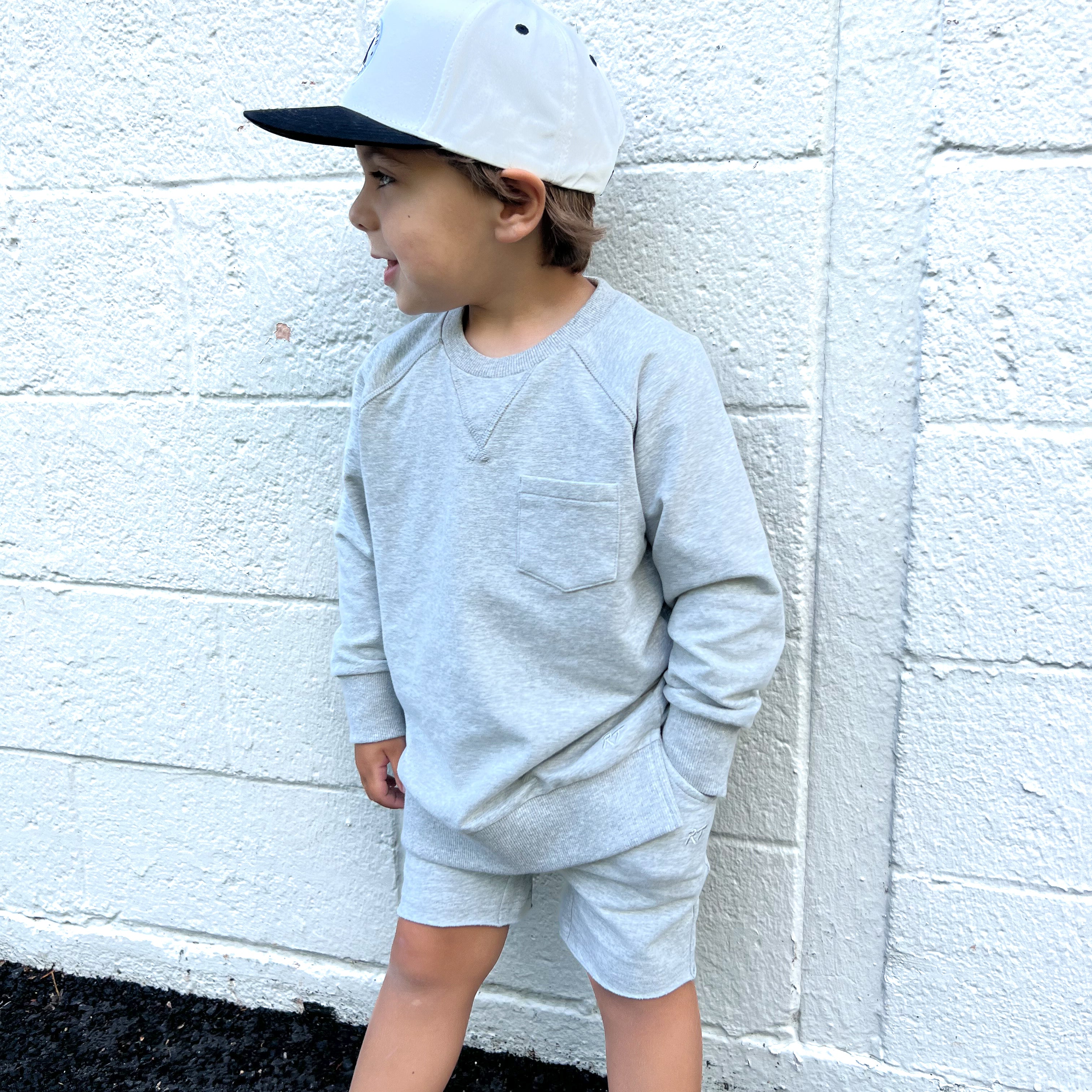 Young boy wearing gray Core Collection toddler shorts, standing outdoors and showcasing the relaxed, above-the-knee fit.