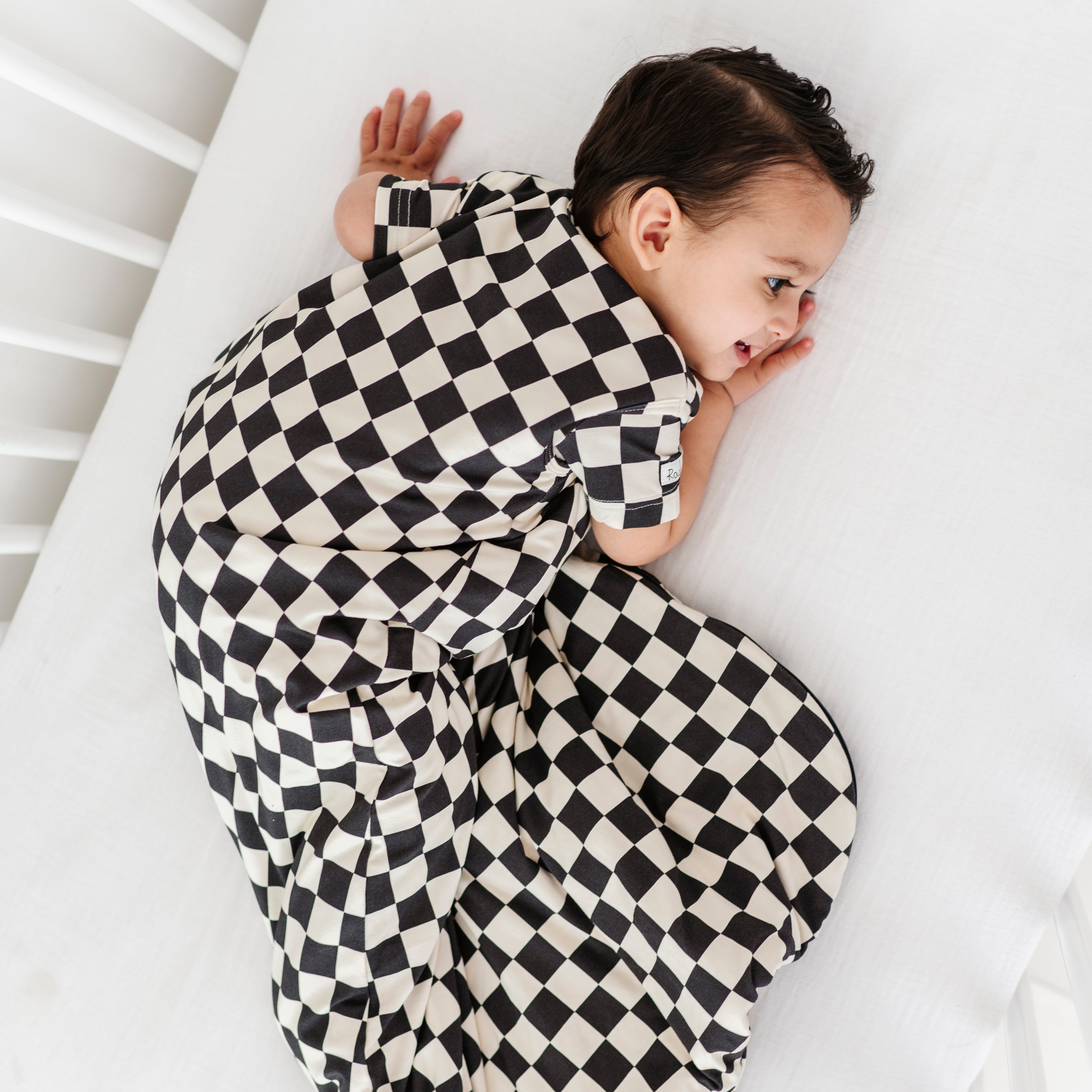 boy wearing Bamboo sleep bag for toddlers in black and white checkered pattern, featuring a two-way zipper by Rad Toddler.