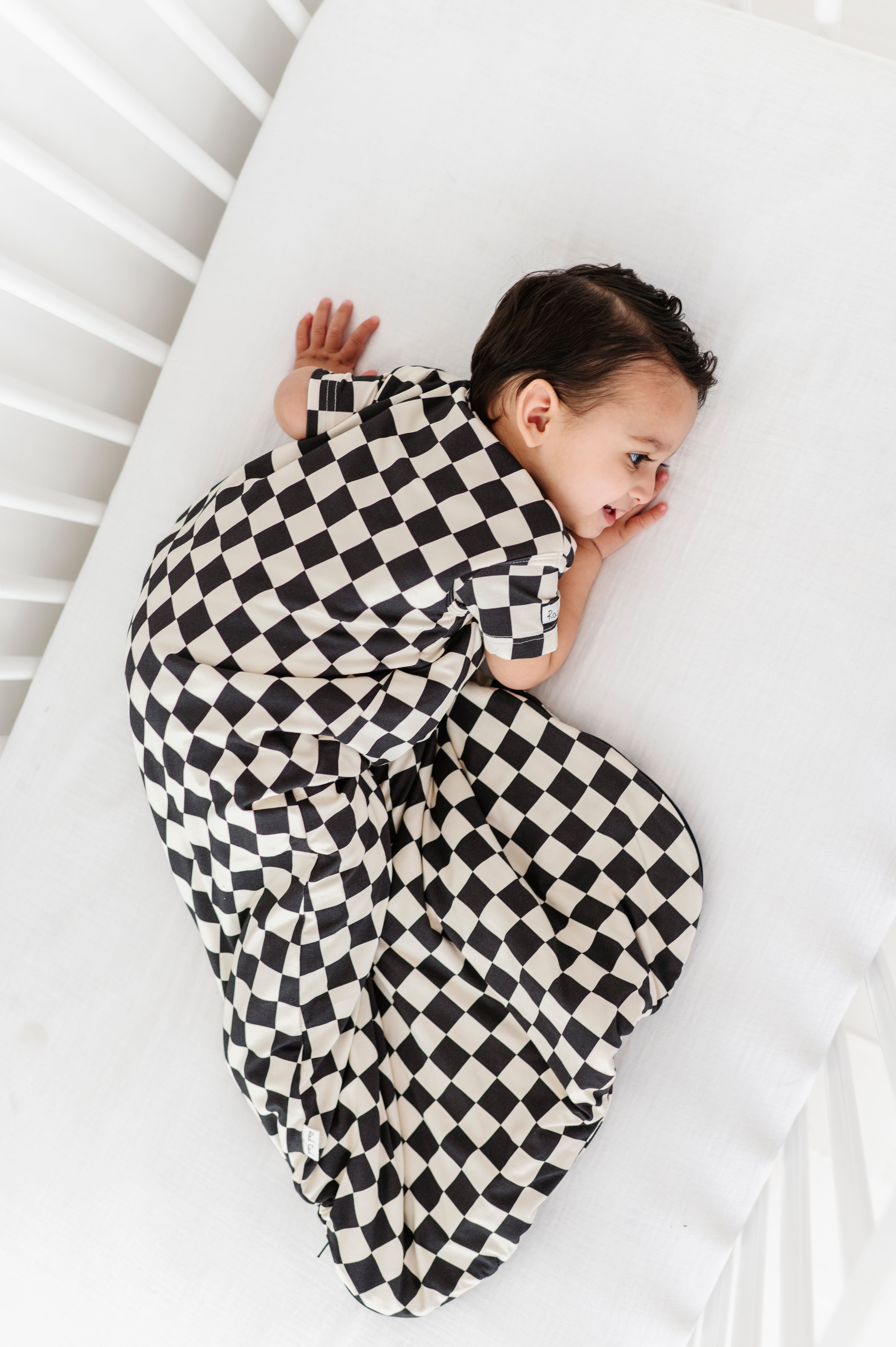 boy wearing Bamboo sleep bag for toddlers in black and white checkered pattern, featuring a two-way zipper by Rad Toddler.