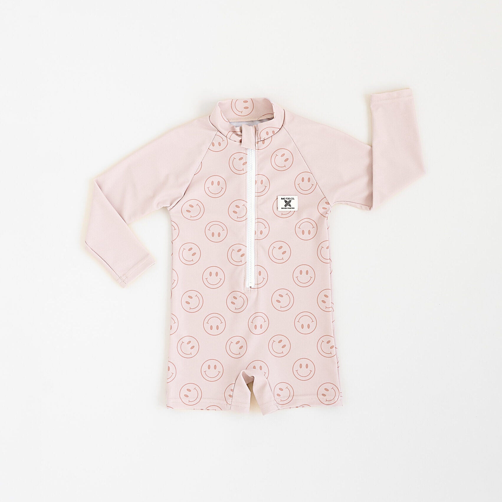 Rad Toddlers Smiley Shore One-Piece Rashguard in beige with smiley face design, featuring easy zipper and UPF 50+ sun protection.