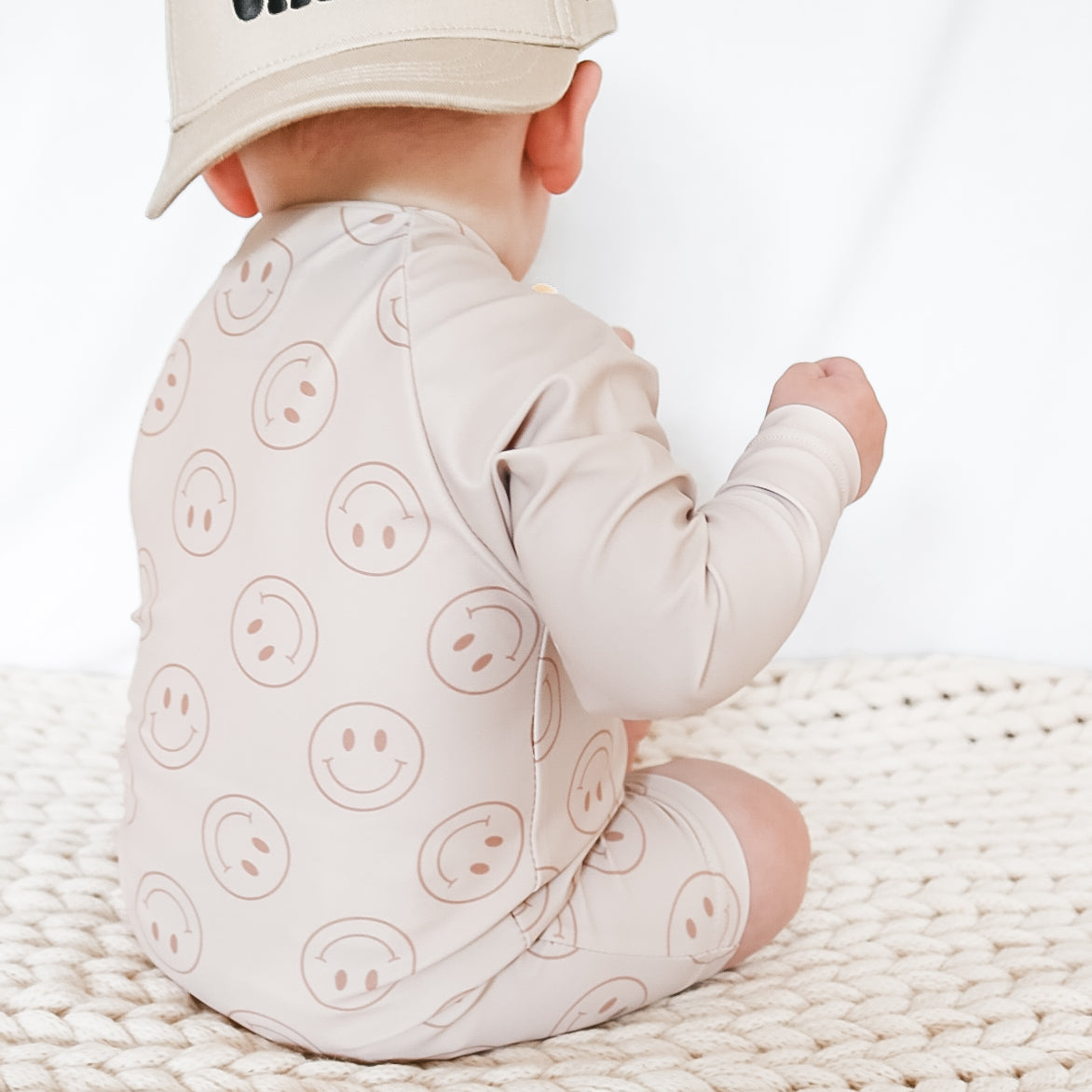 boy wearing Rad Toddlers Smiley Shore One-Piece Rashguard in beige with smiley face design, featuring easy zipper and UPF 50+ sun protection.