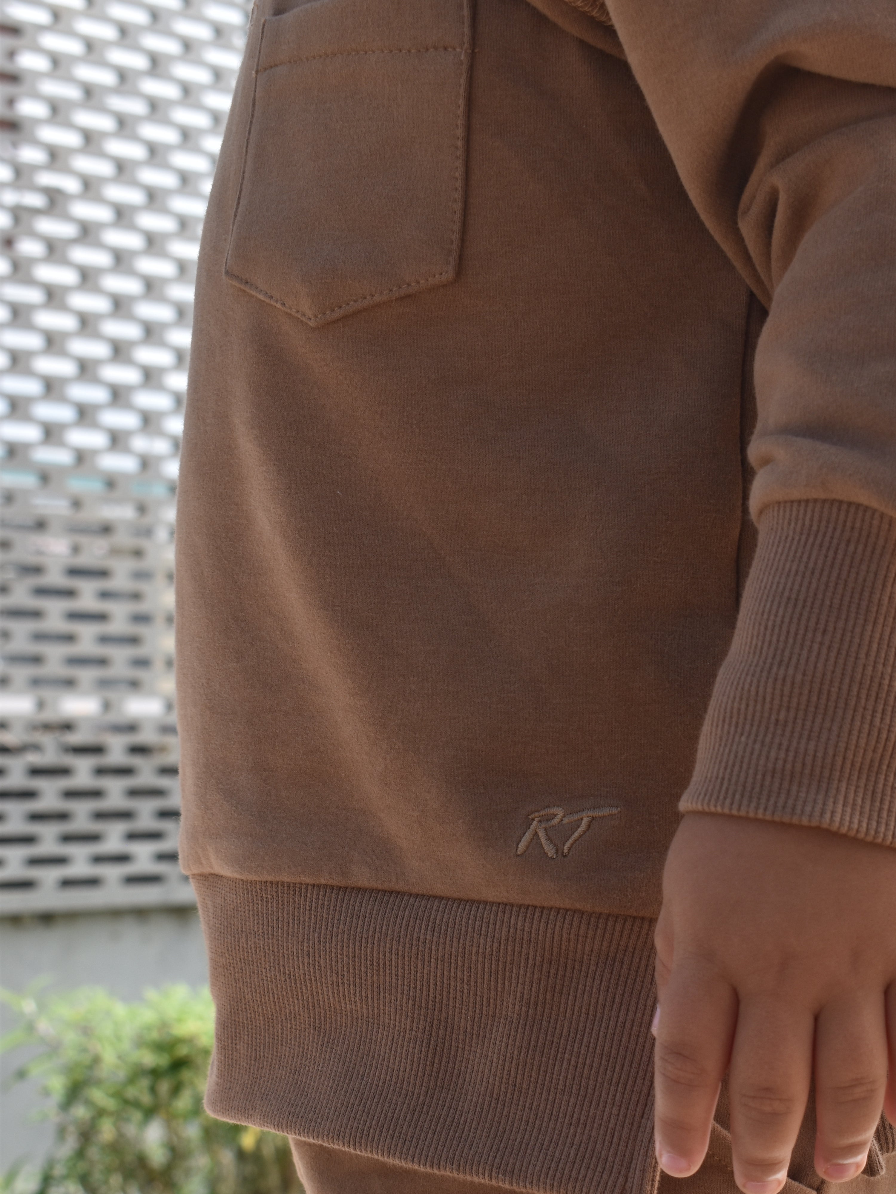 Young boy wearing almond Core Collection toddler crewneck with oversized fit, standing outdoors.