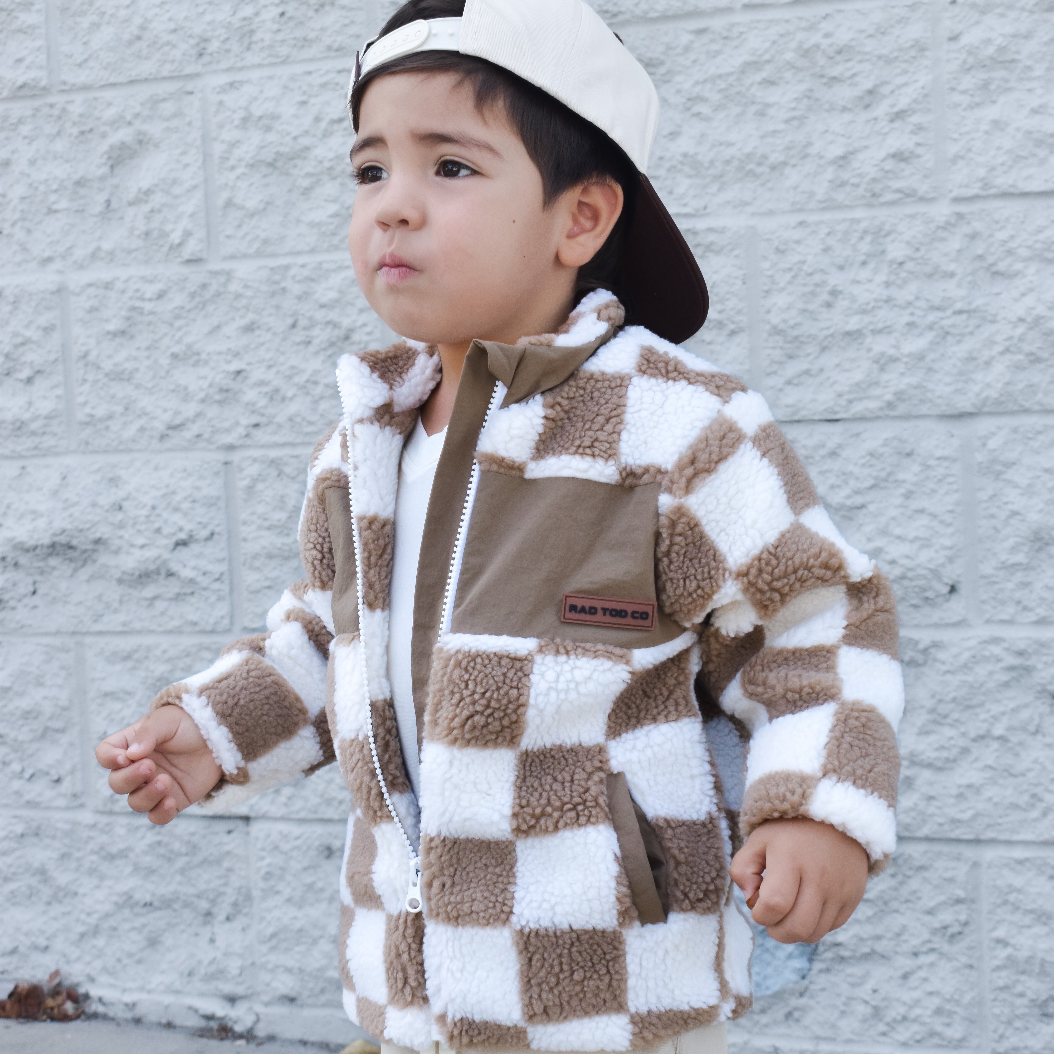 Child wearing teddy Checkerboard Sherpa jacket in beige checker pattern – zip-up design