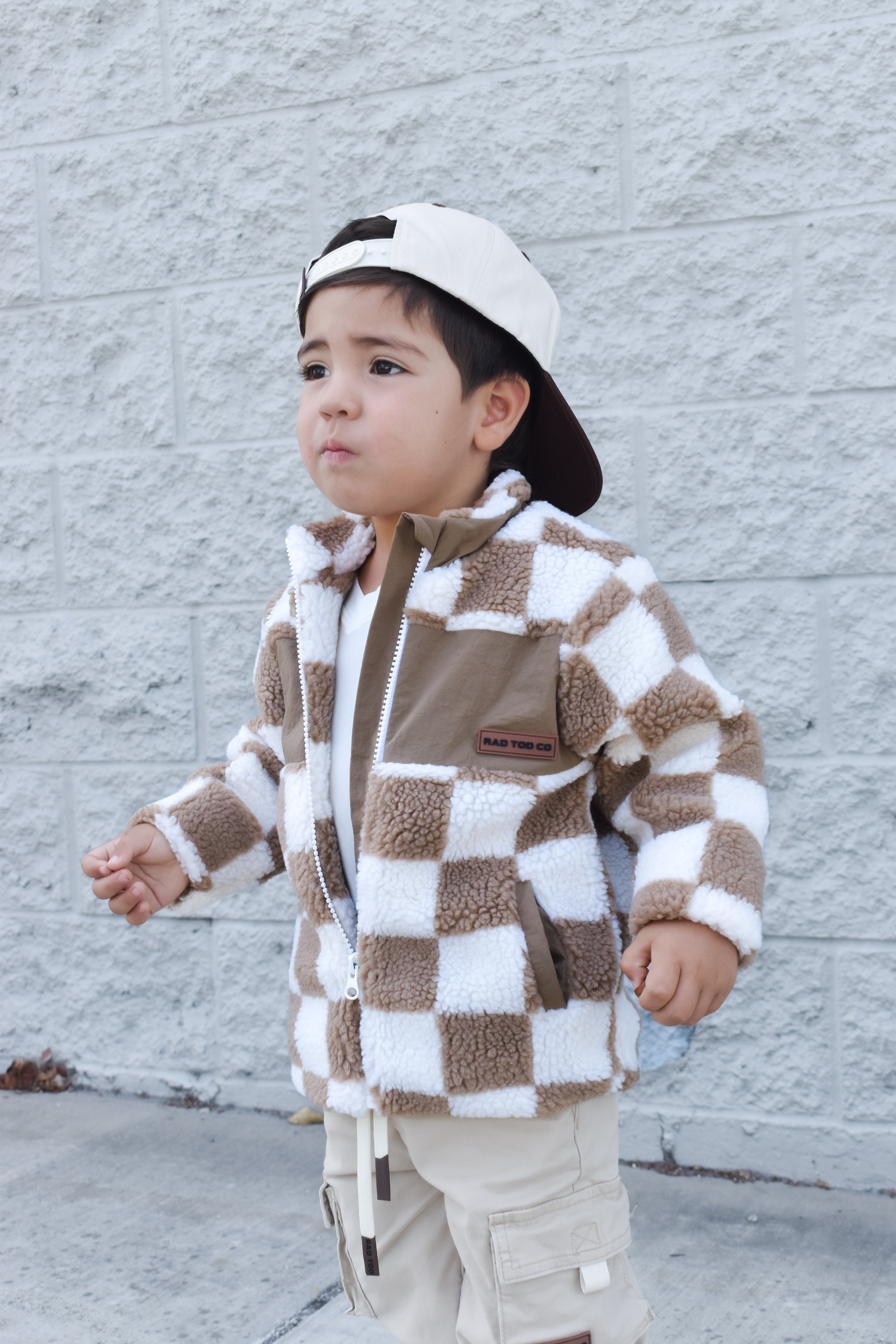 Child wearing teddy Checkerboard Sherpa jacket in beige checker pattern – zip-up design