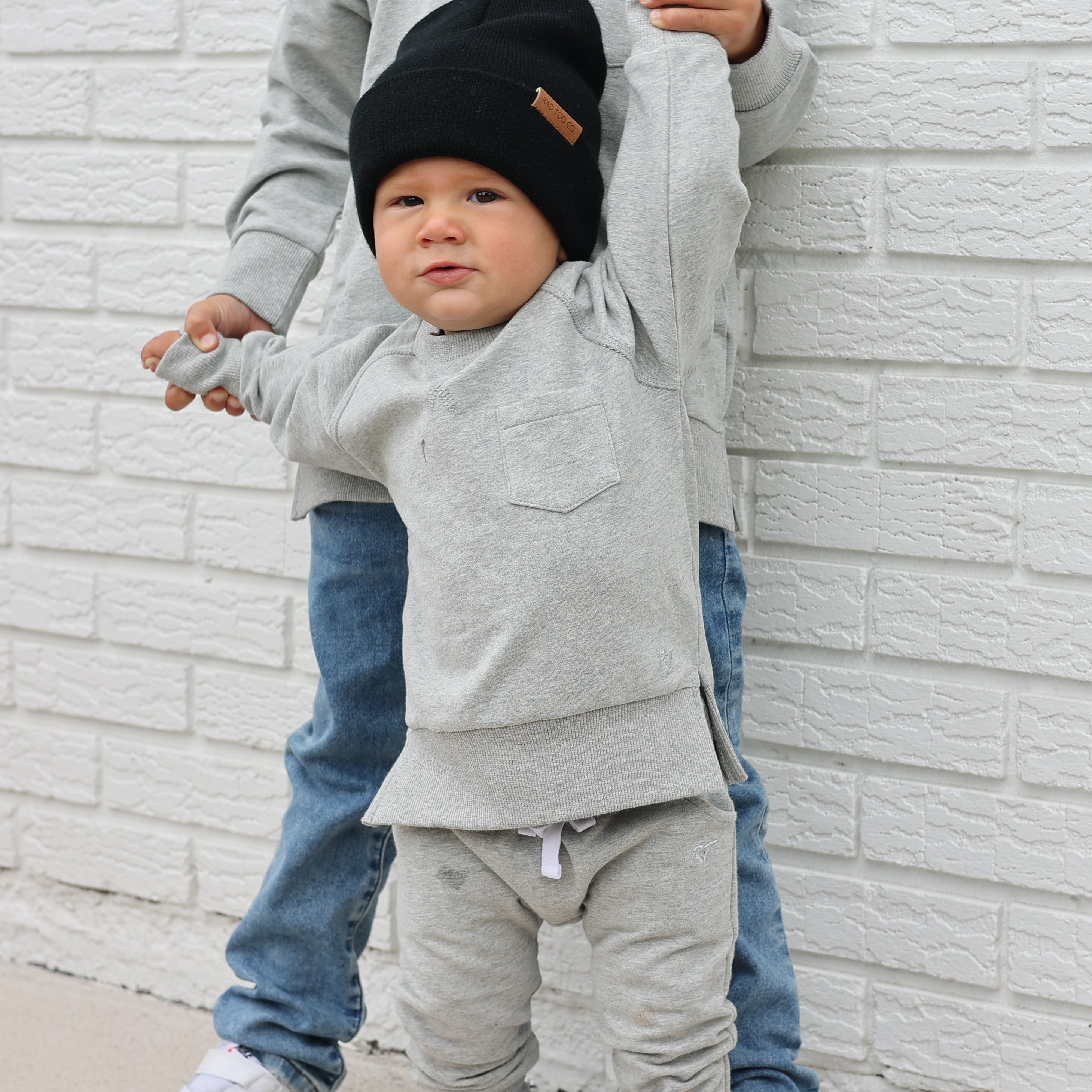Young boy wearing gray Core Collection toddler crewneck with oversized fit, standing outdoors.