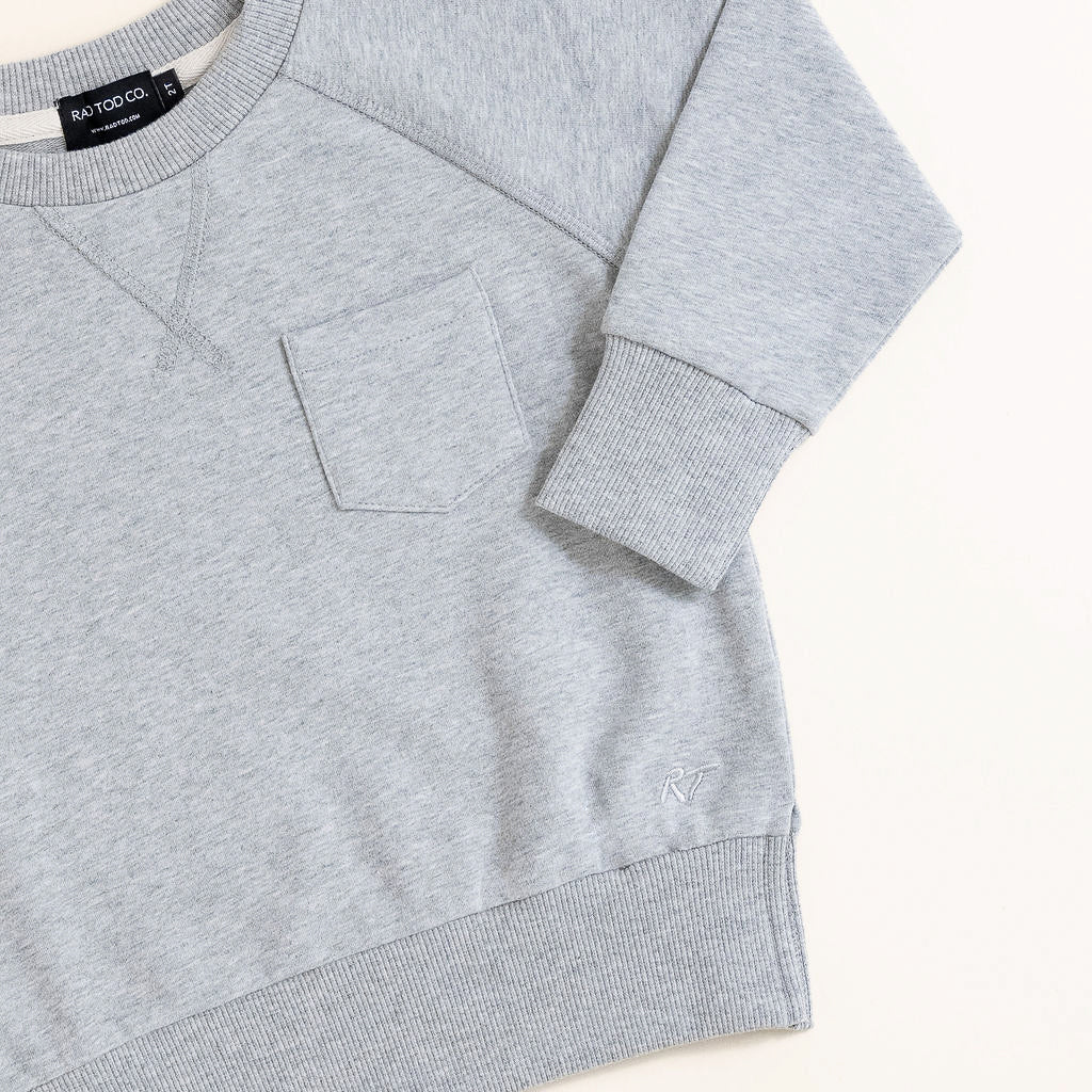 Flat lay of gray toddler crewneck from the Core Collection with oversized, boxy fit and RT embroidered logo.