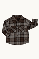A long-sleeve plaid button-up shirt in brown, beige, and gray, featuring two chest pockets and a small white 'RAD TODDLER CO' logo on the lower right hem, displayed flat against a light off-white background.