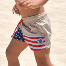 Americana toddler swim shorts featuring a beige upper, red and white stripes, blue star pattern, elastic waistband, and vintage-inspired patriotic design for boys.