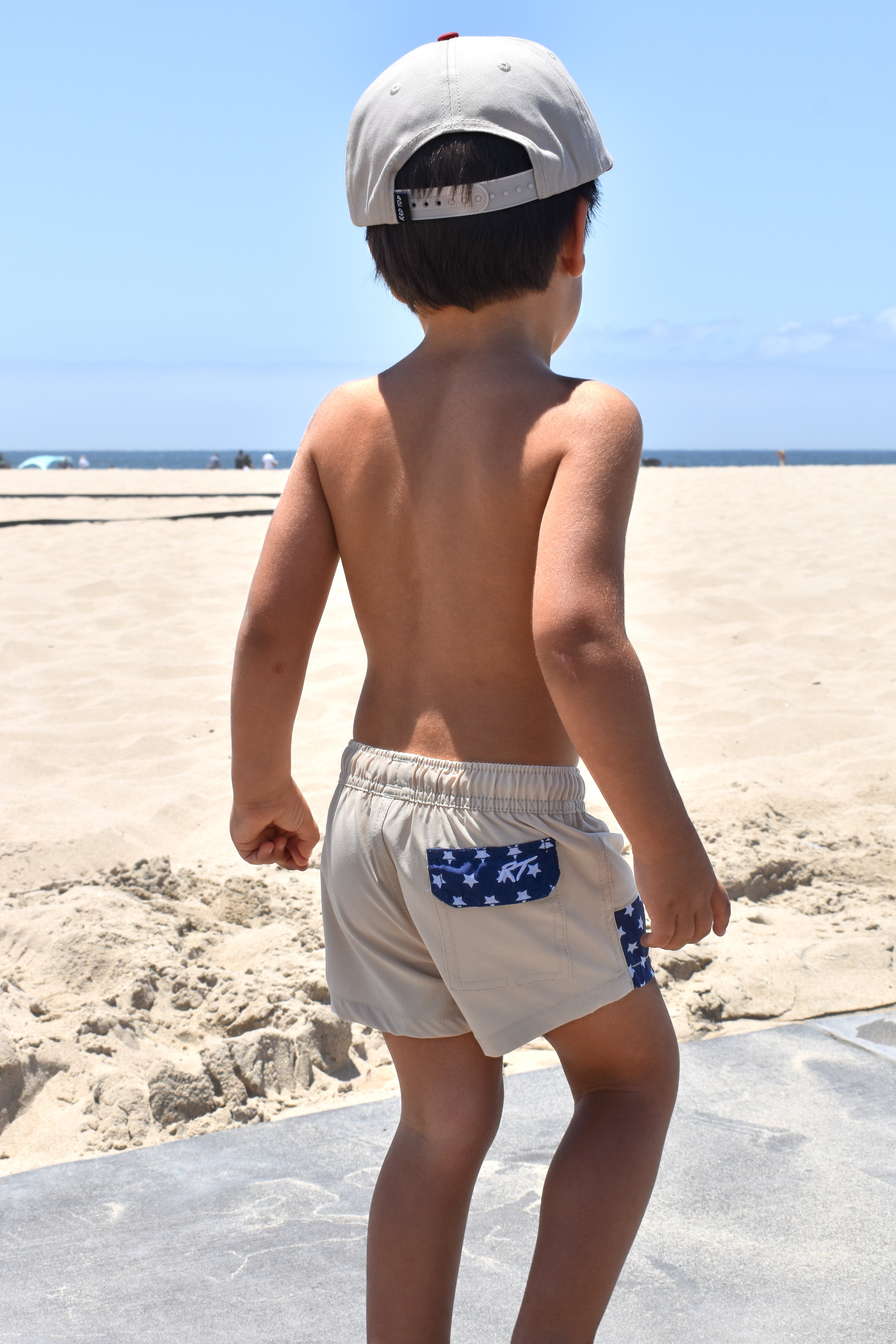 Boy standing on beach wearing Americana swim shorts 