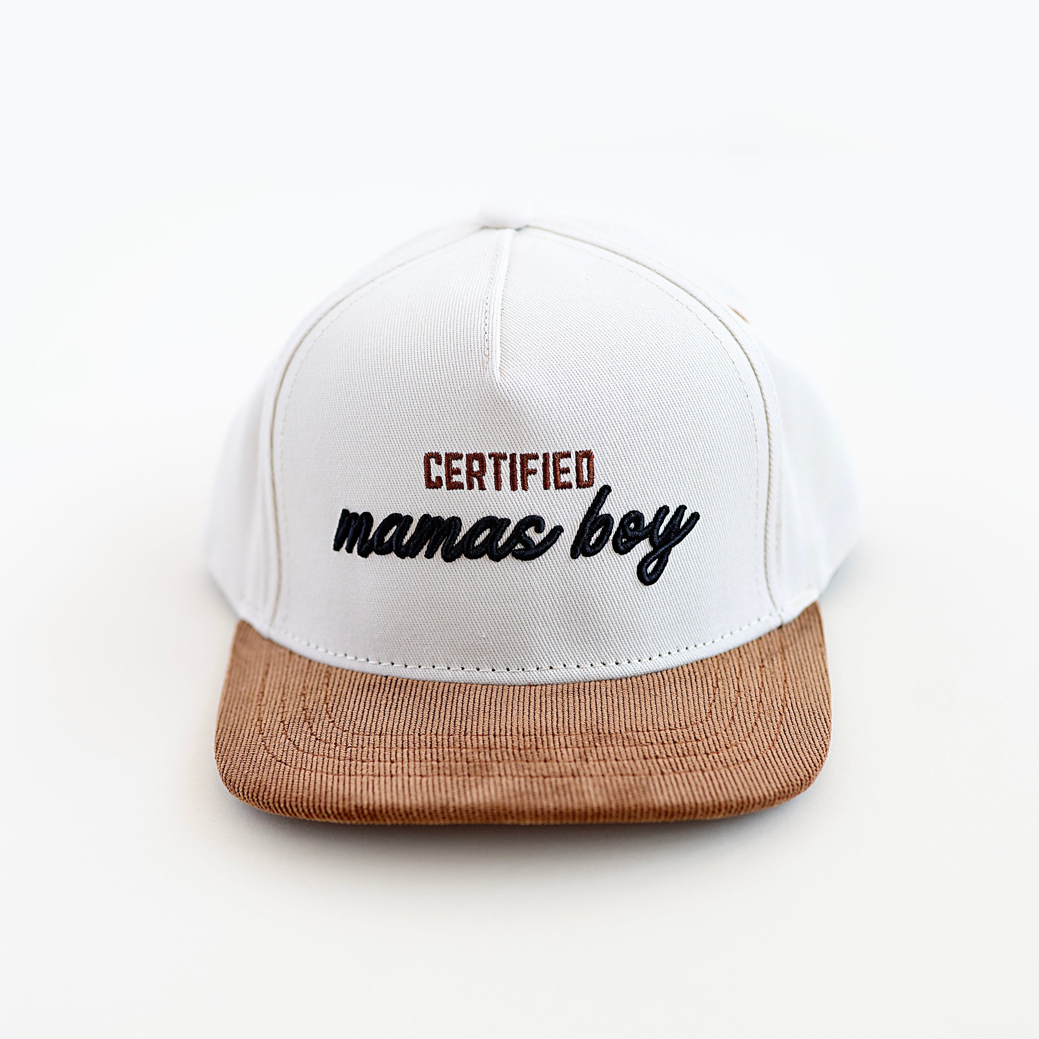 A beige, black, and brown toddler snapback cap with 'CERTIFIED mamas boy' embroidered in black on the front.