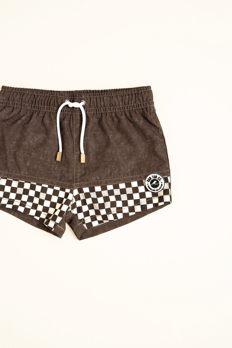 Brown shorts with a checkered pattern and brand logo on a white background