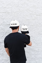 Dad wearing Hi, I’m Dad snapback outdoors while spending time with child.