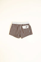 Brown and white patterned shorts with a logo on a beige background