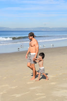 Man and child walking on a beach with ocean and sky in the background while matching in Rad Toddler Shorts