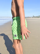 Kids wearing lime green hi-vis checker hybrid swim shorts at the beach