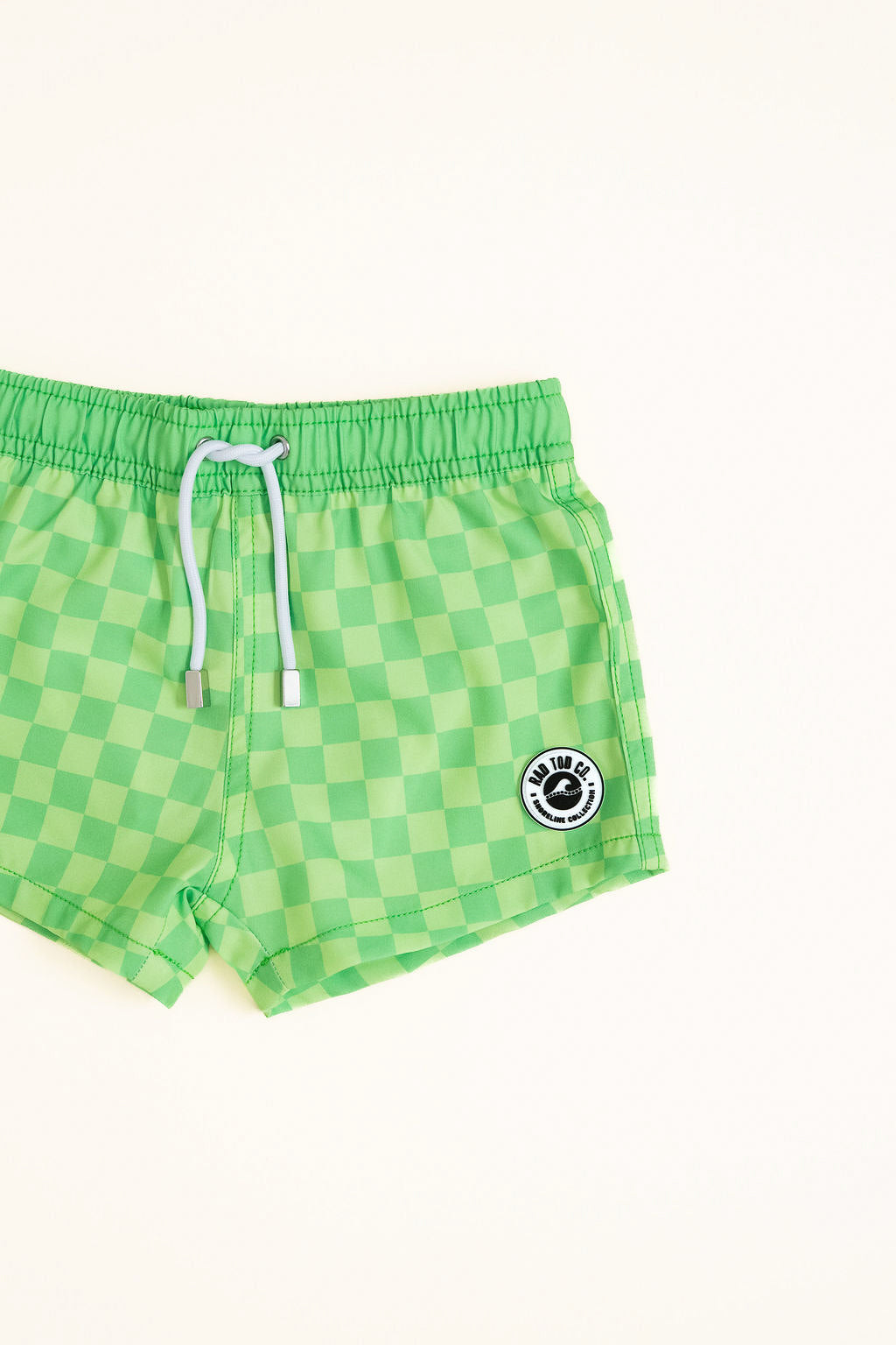 Green checkered shorts with a Rad Toddler logo on a white background detail shot