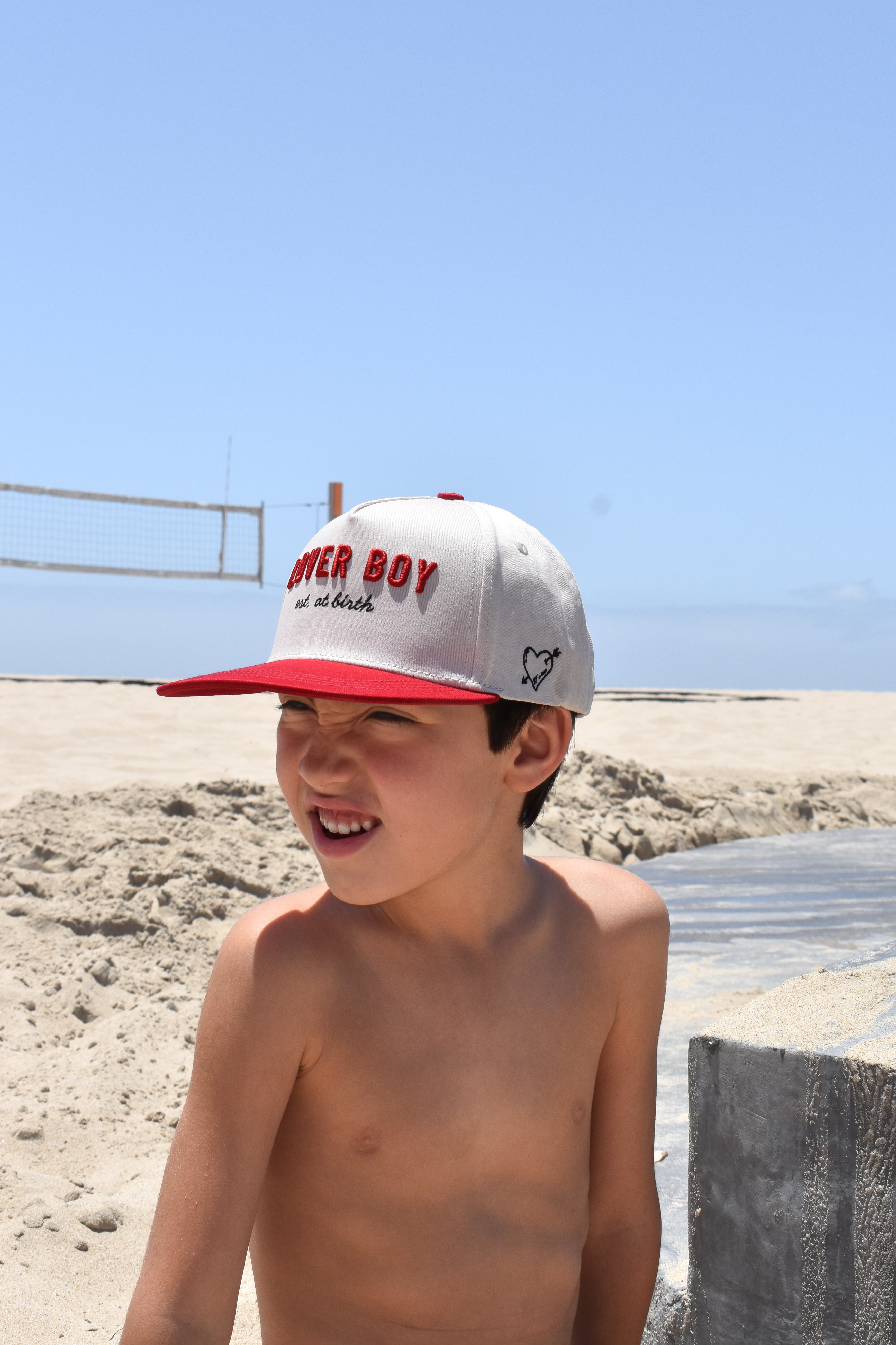 Young boy wearing a cap with Lover Boy hat on a beach