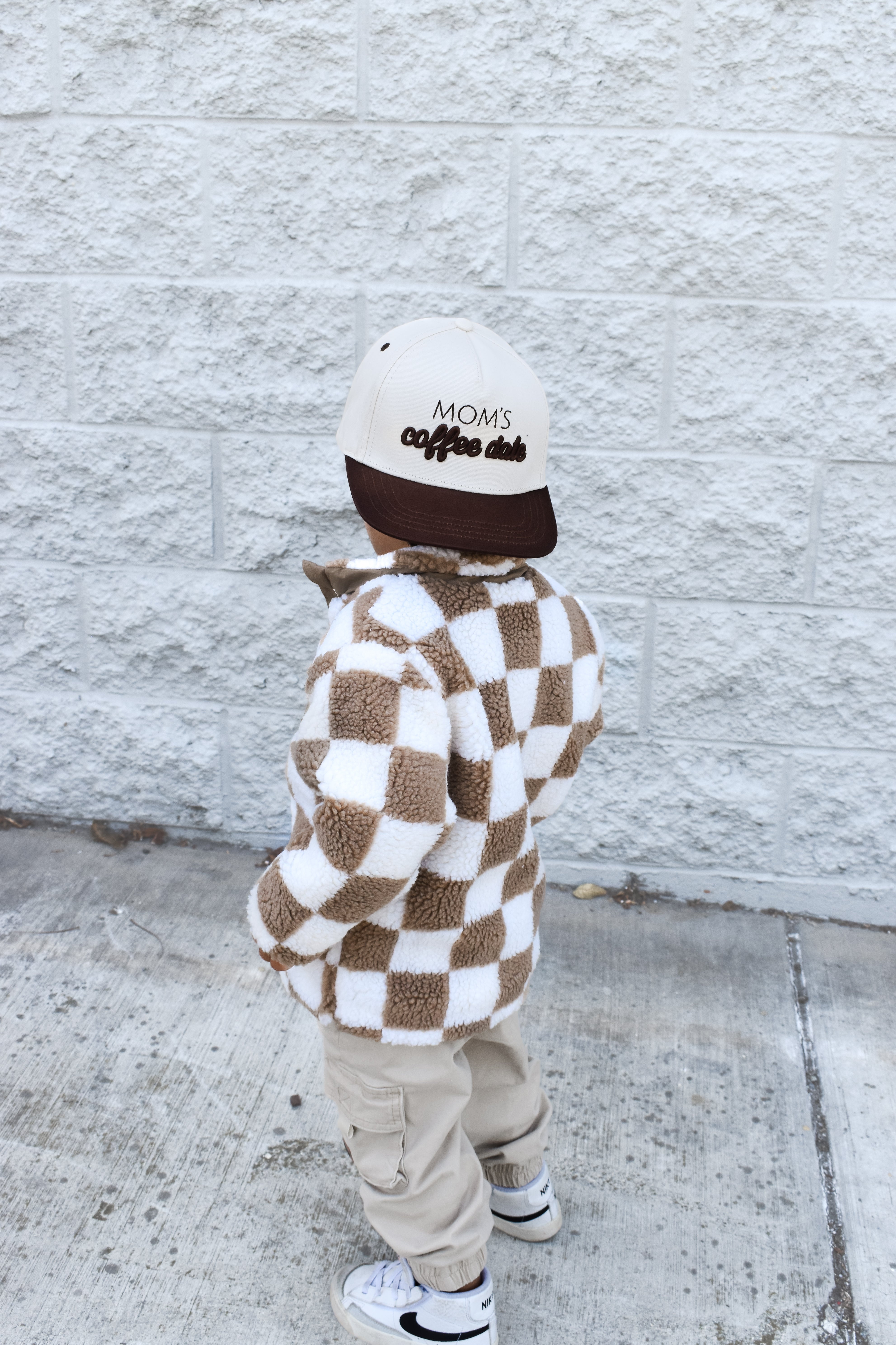 Child wearing the Moms Coffee Date snapback while playing outdoors.