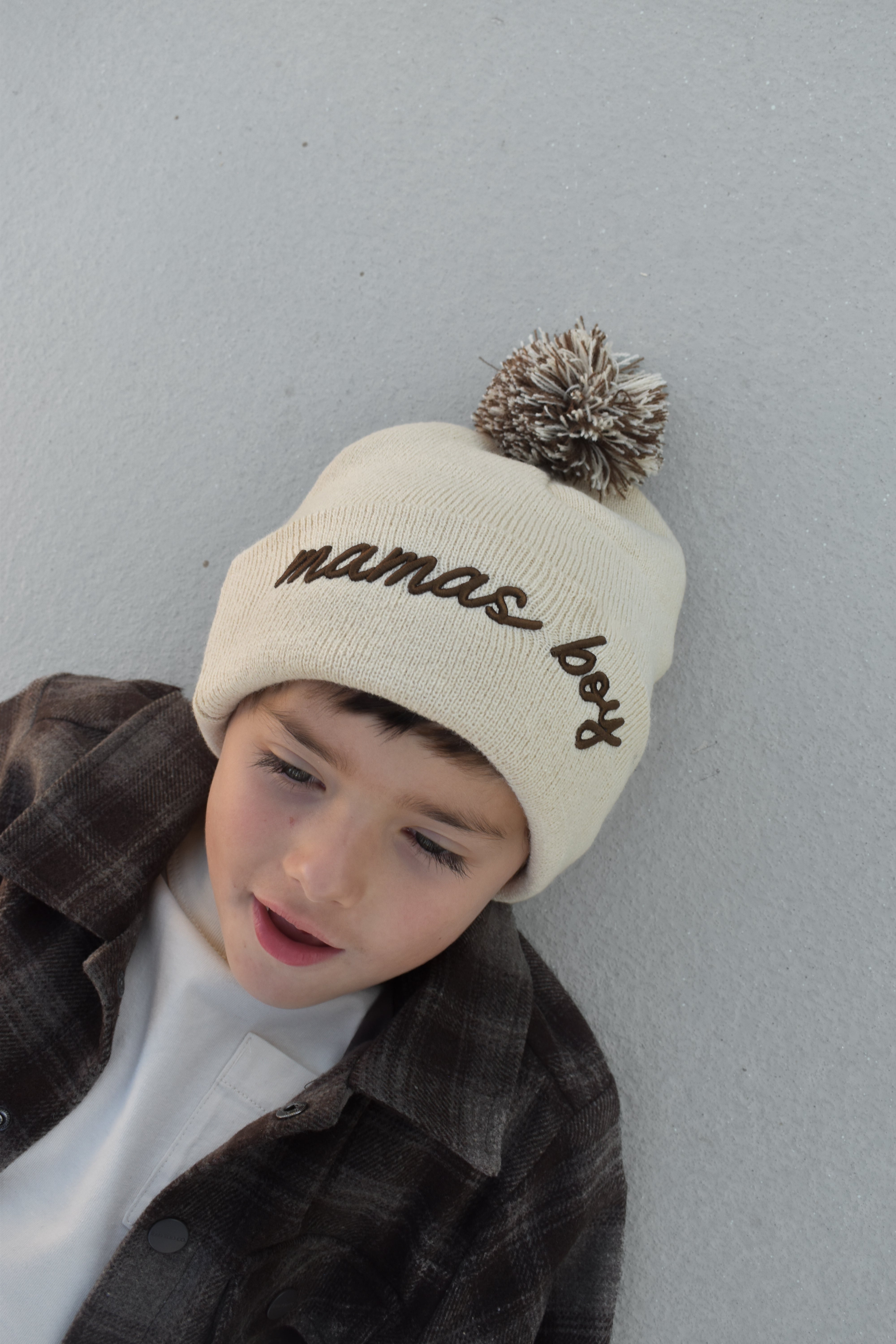 Toddler wearing beige Mamas Boy beanie with brown lettering