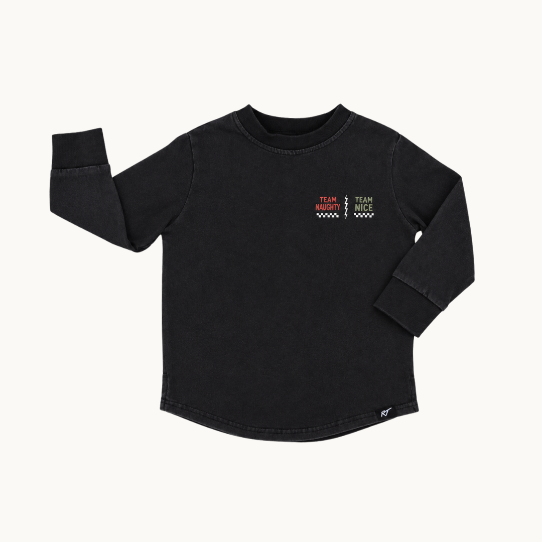 A black long-sleeve crewneck shirt with a small graphic on the left chest reading 'TEAM naughty TEAM nice' in red, green, and white, displayed on a light off-white background.