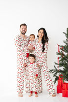 Family of four wearing matching pajamas in front of a Christmas tree with presents.