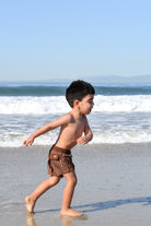 boy wearing Pinstripe Espresso swimmies by rad toddler on a beach