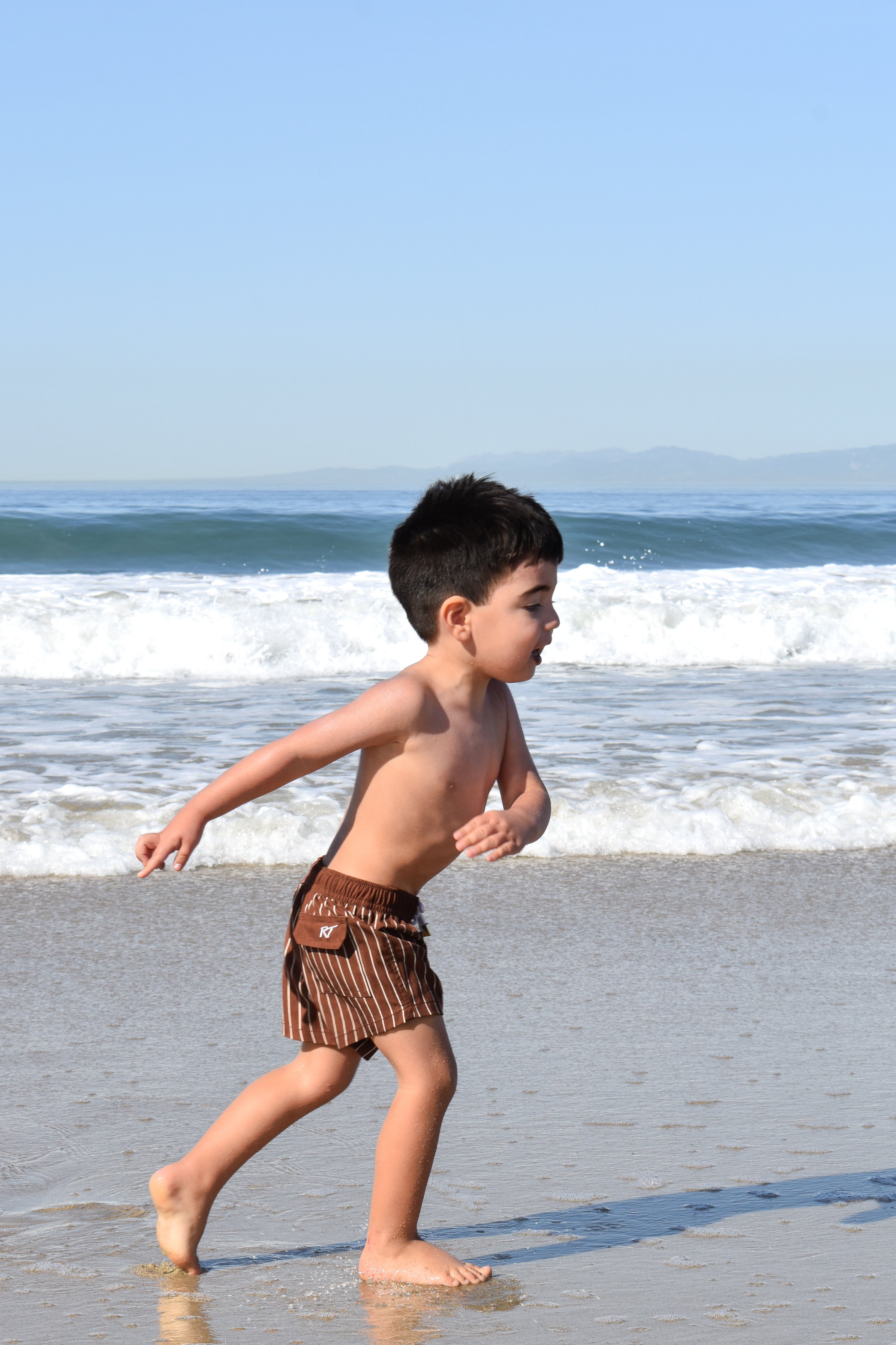 boy wearing Pinstripe Espresso swimmies by rad toddler on a beach