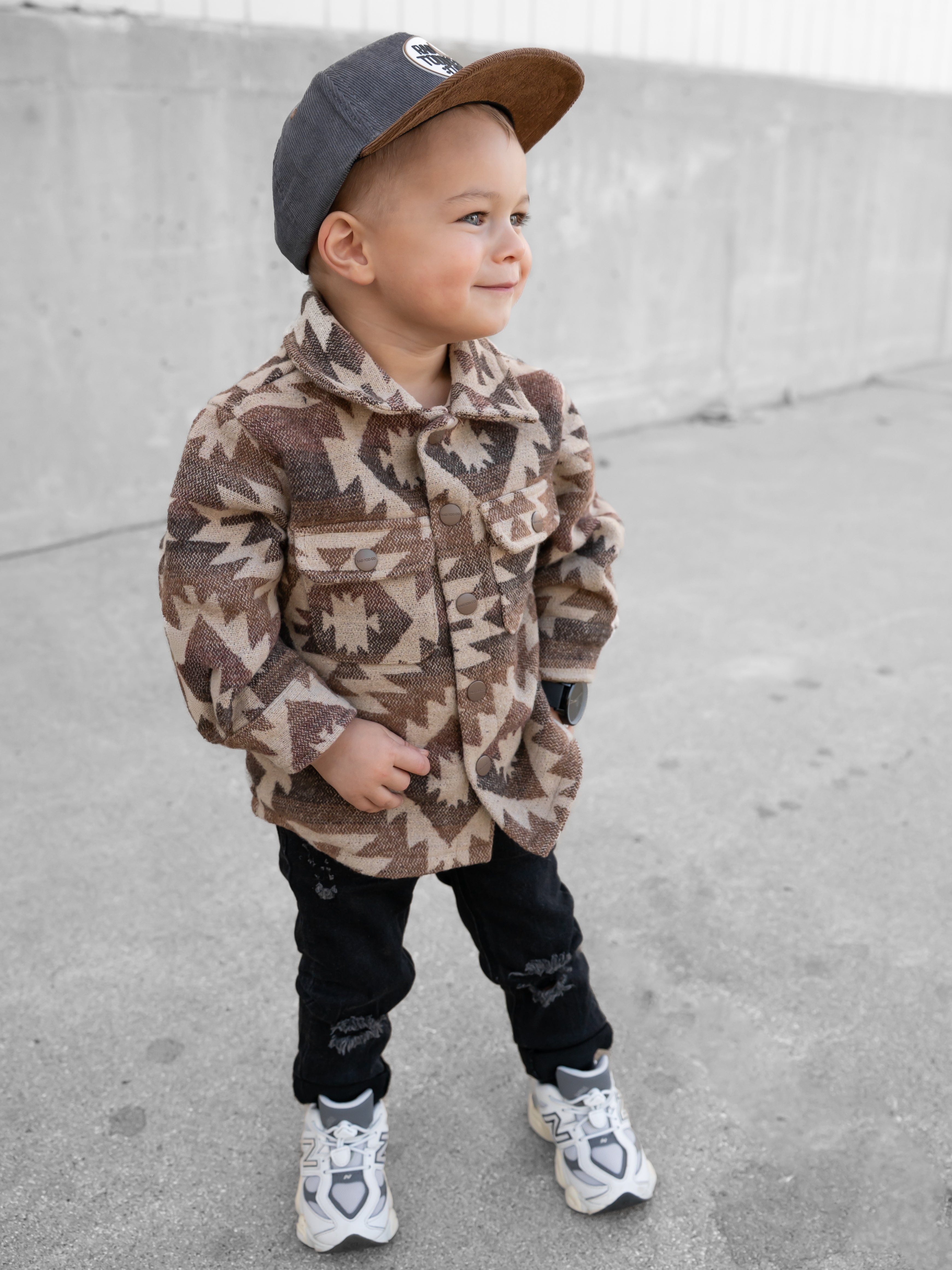 Child wearing RAD TODDLER Skate Club snapback outdoors while playing.
