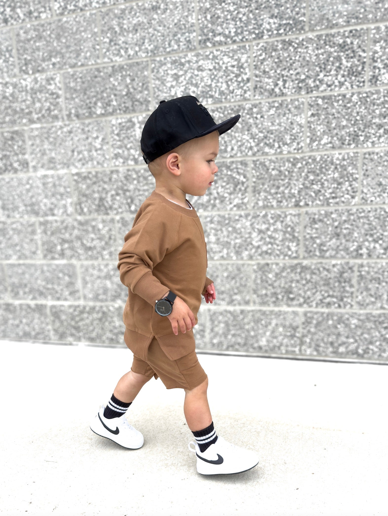 Young boy wearing almond Core Collection toddler set, standing outdoors and showcasing the relaxed, above-the-knee fit.