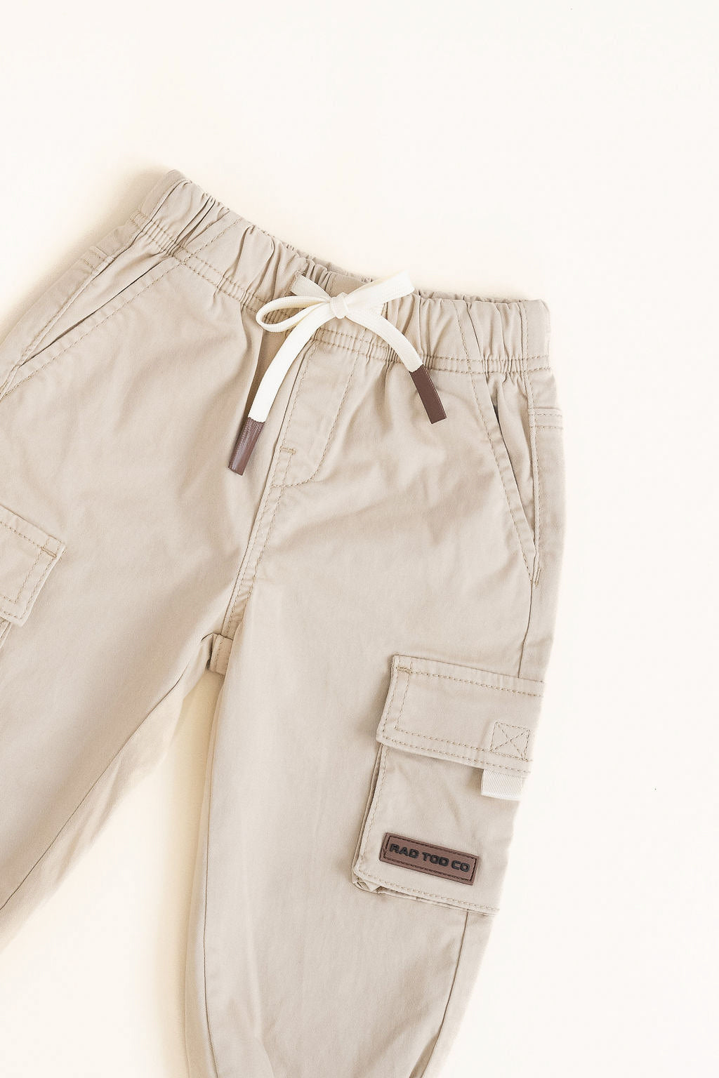Beige cargo pants with a drawstring on a white background