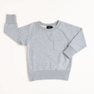 Flat lay of gray toddler crewneck from the Core Collection with oversized, boxy fit and RT embroidered logo.