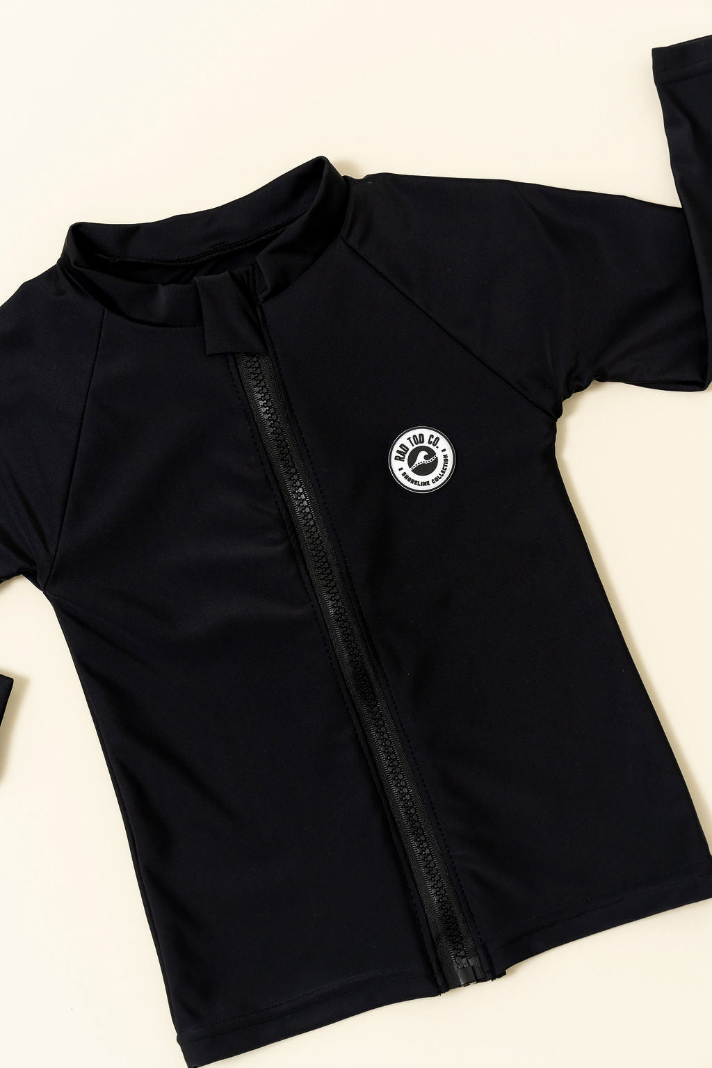 Black zip-up shirt with a logo on a light beige background